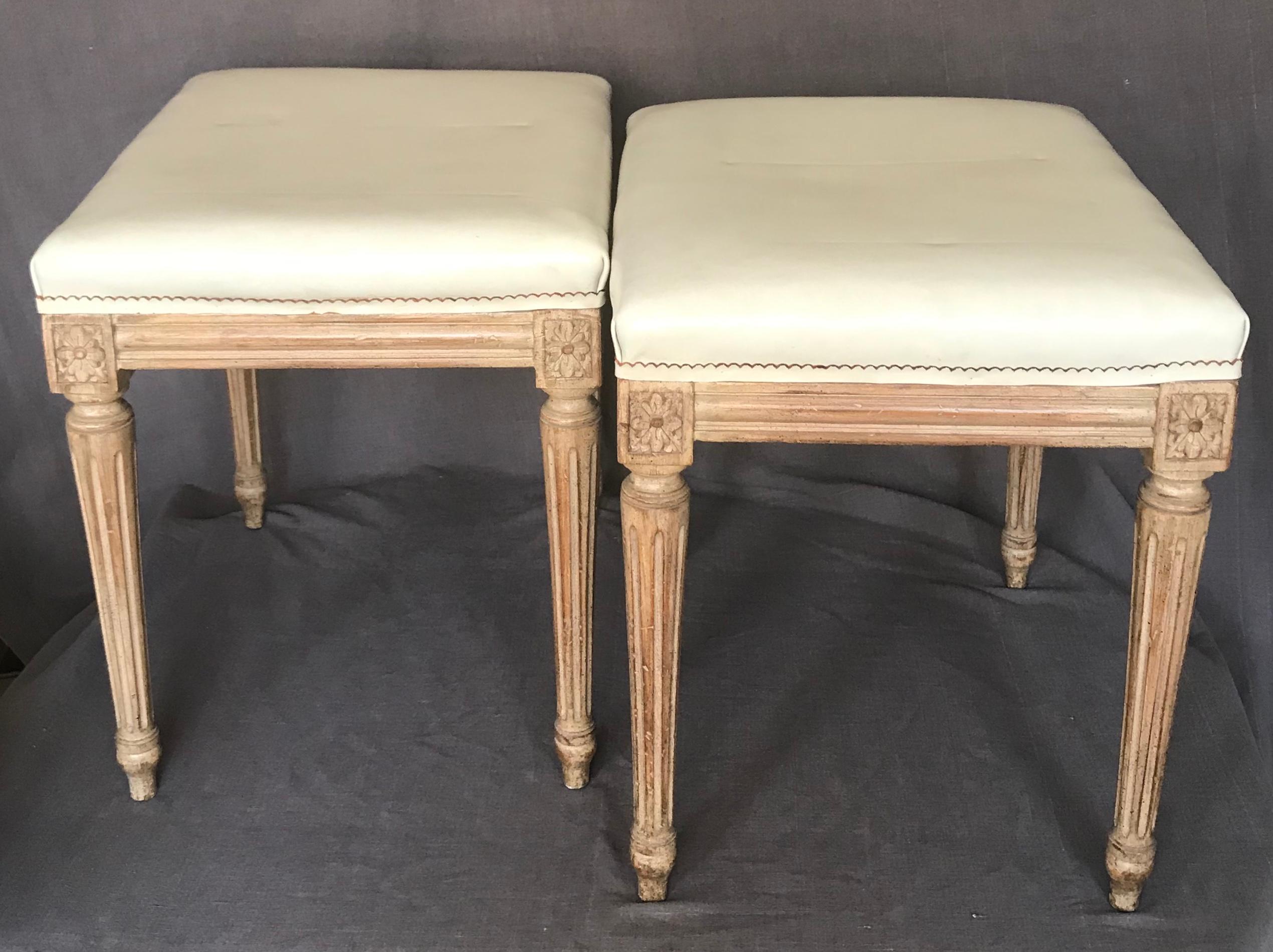 Pair of midcentury Louis XVI stools in the manner of Jansen. Urbane pair pale carved wood stools with reeded legs covered in original chic cream Naugahyde, France, circa 1940.
Dimensions: 14” D x 17” W x 17.5” H.