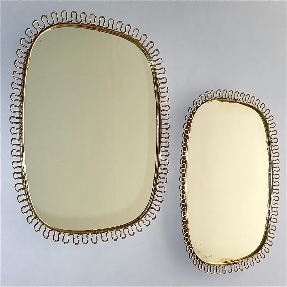Sculptural and elegant pair of midcentury wall mirrors by Josef Frank Austria / Sweden for Svenskt Tenn, circa 1940-1950 which are made of patinated brass metal, a beautiful brass loop-wire-decoration, original mirror glass and solid wood at the