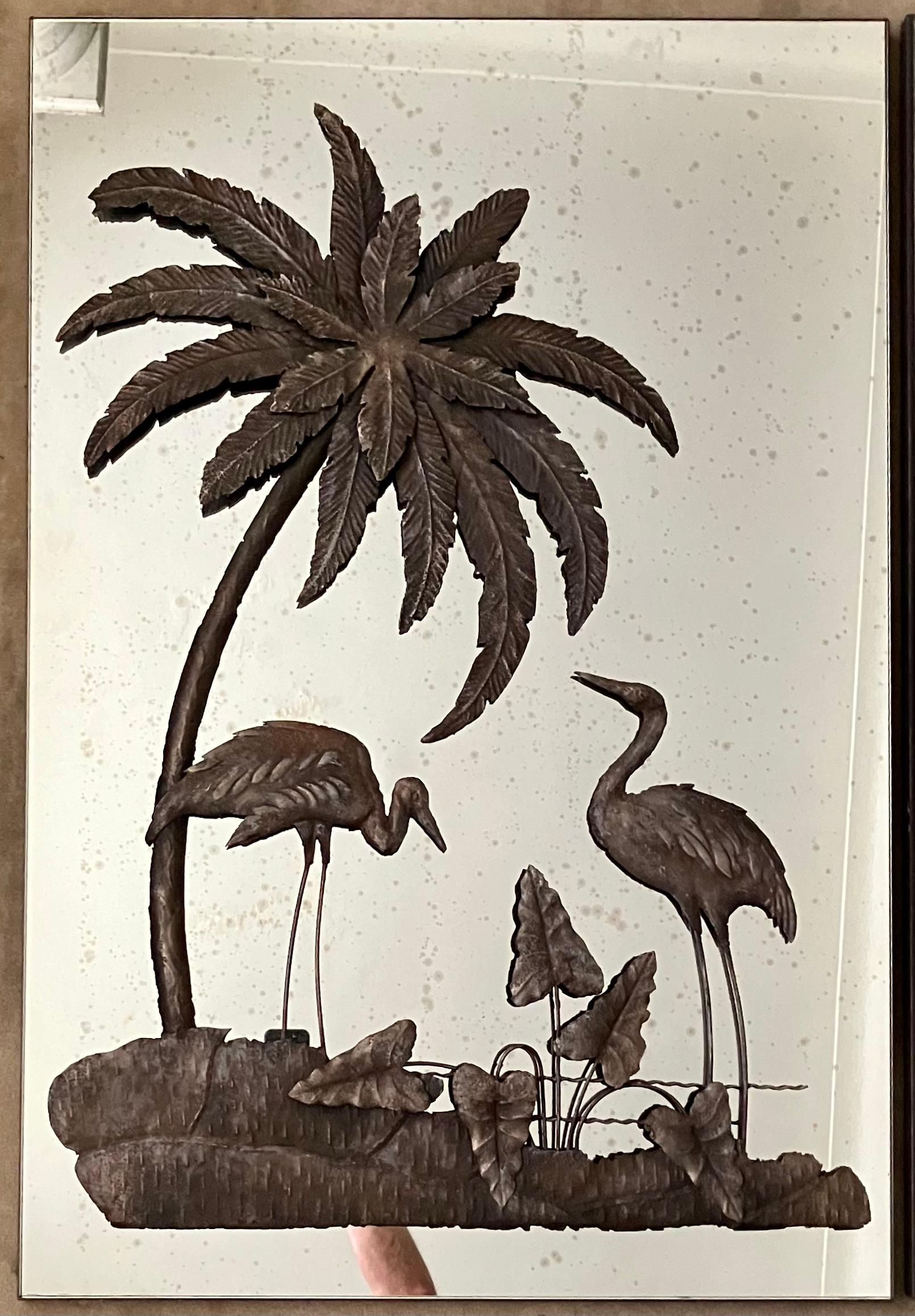Pair mirror bird panels. Set of two vintage bronze colored metal large wall decorations with tropical foliage of palms and palmetto grasses with pairs of herons in a thirties chinoiserie style now applied to wood backed mercury glass panels. United