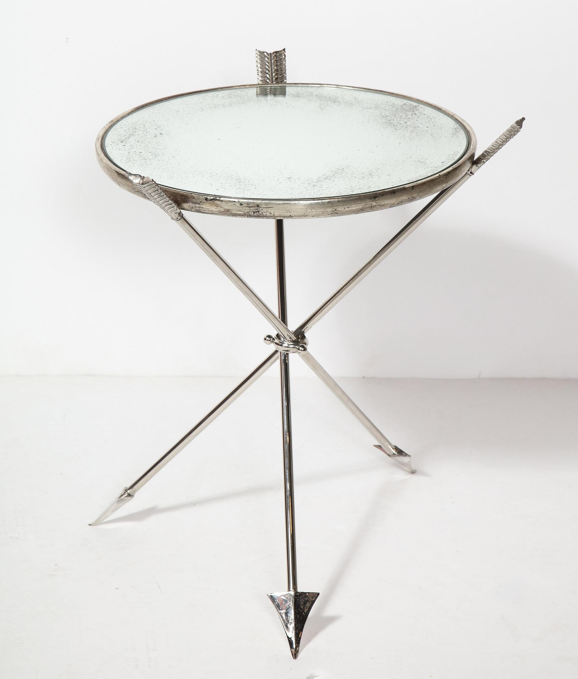 Pair of arrow form mirrored tables

The pair of tables with silver gilt framed mirrored tops supported by a tripod base, each leg in the form of an arrow.