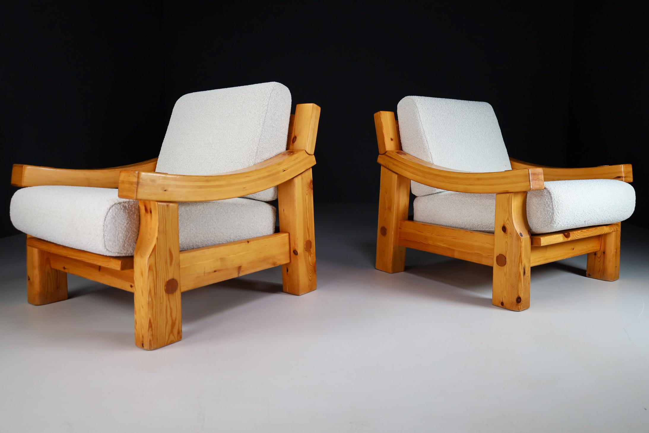 Pair of lounge chairs with sturdy frames in solid French pine Re-upholstered Bouclé wool fabric, France, 1970s. The grain of the wood is nicely visible, especially on the sturdy curved armrests. Thick Bouclé cushions provides seating comfort.