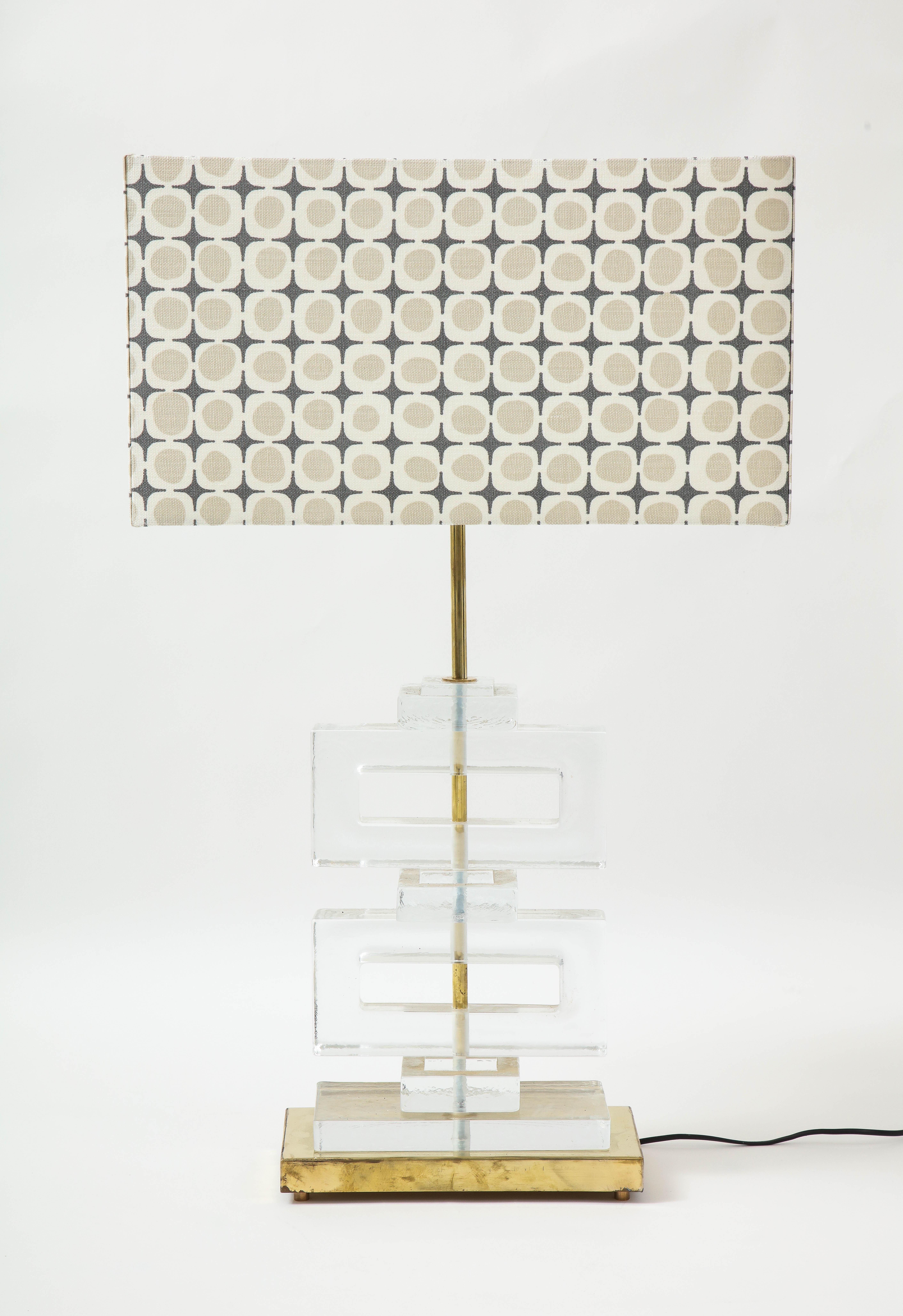 A pair of 21st century molded clear glass Murano lamps. The clear blocks are a classic Mid Century modern motif seen often in screens. The glass blocks sit on a brass base and have a brass rod. A wonderful custom-made lampshade completed the look.