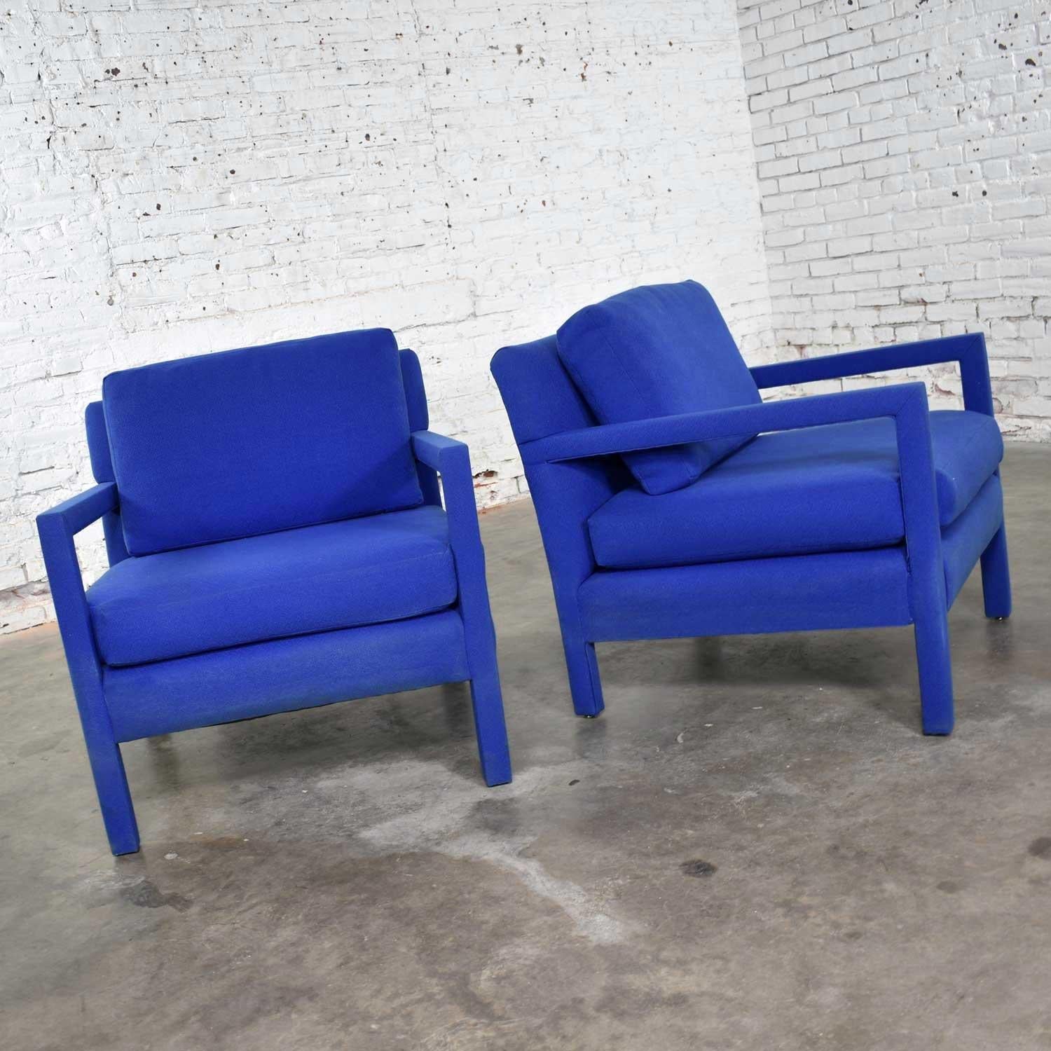 Handsome pair of royal blue or cobalt blue fully upholstered modern Parsons style club chairs after a design by Milo Baughman. They are in wonderful vintage condition. We are unsure if this is the original upholstery. It does have some signs of age