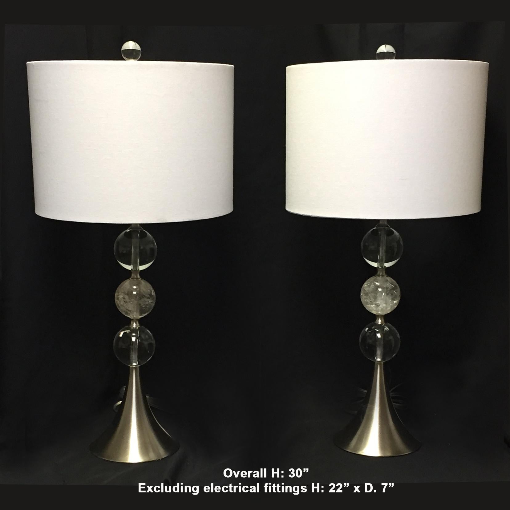 Lovely pair of modern style rock crystal lamps.
The crystal finial is over a round white fabric shade above a steel shaft with two crystal balls centered with a hand carved and hand polished rock crystal ball.
Late 20th century. 

Shades are