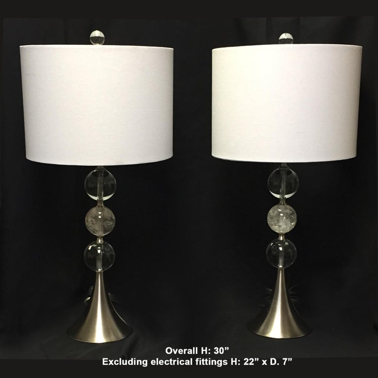 Lovely pair of modern style rock crystal lamps.
The crystal finial is over a round white fabric shade above a steel shaft with two crystal balls centered with a hand carved and hand polished rock crystal ball.
Late 20th century. 

Shades are