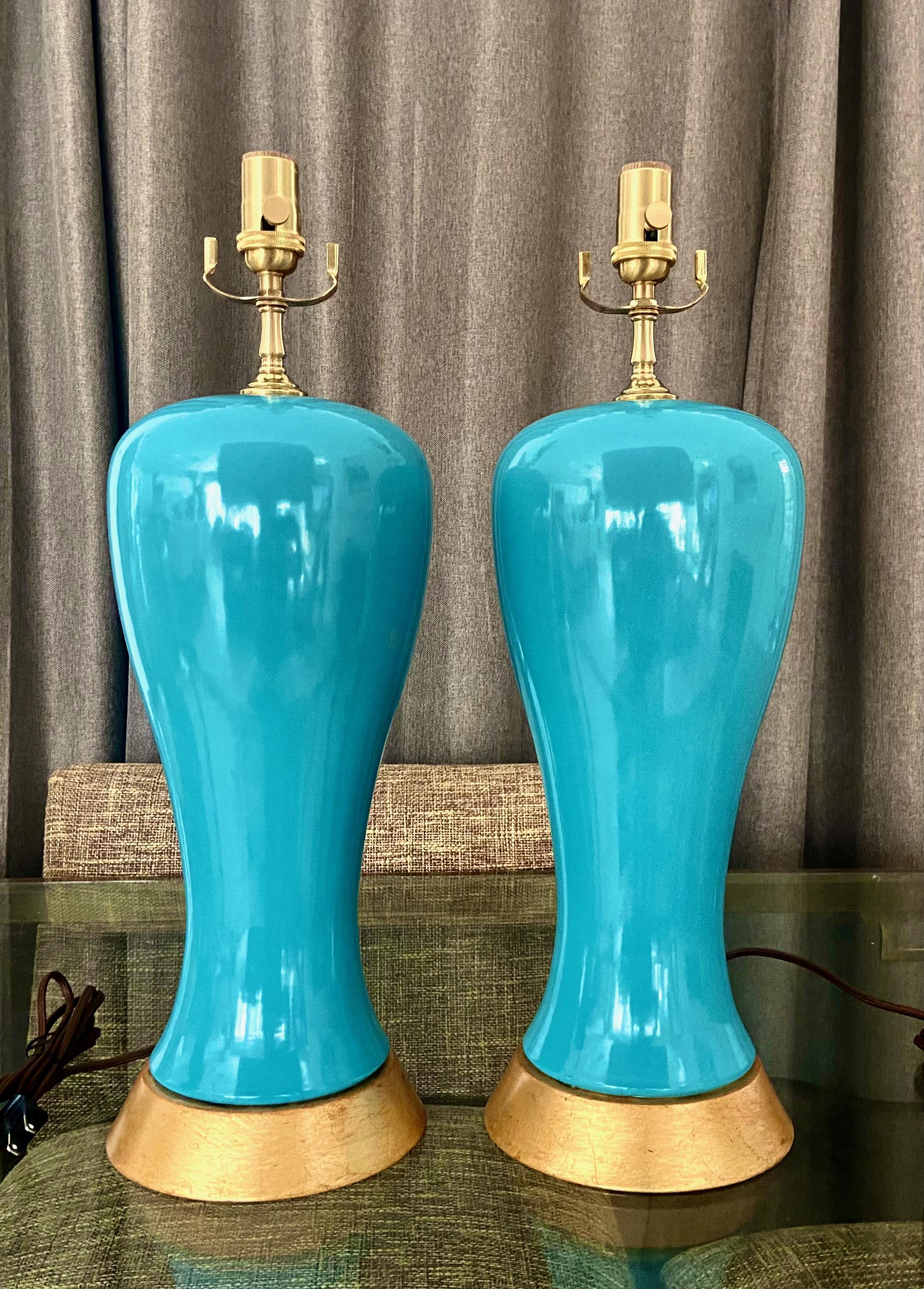 Pair of chic turquoise modern plum form ceramic table lamps on gilt metal bases. The vases have an Asian flair and fit perfectly in a modern or traditional setting. New 3 way brass sockets, fittings and rayon covered cords. Vase portion 15