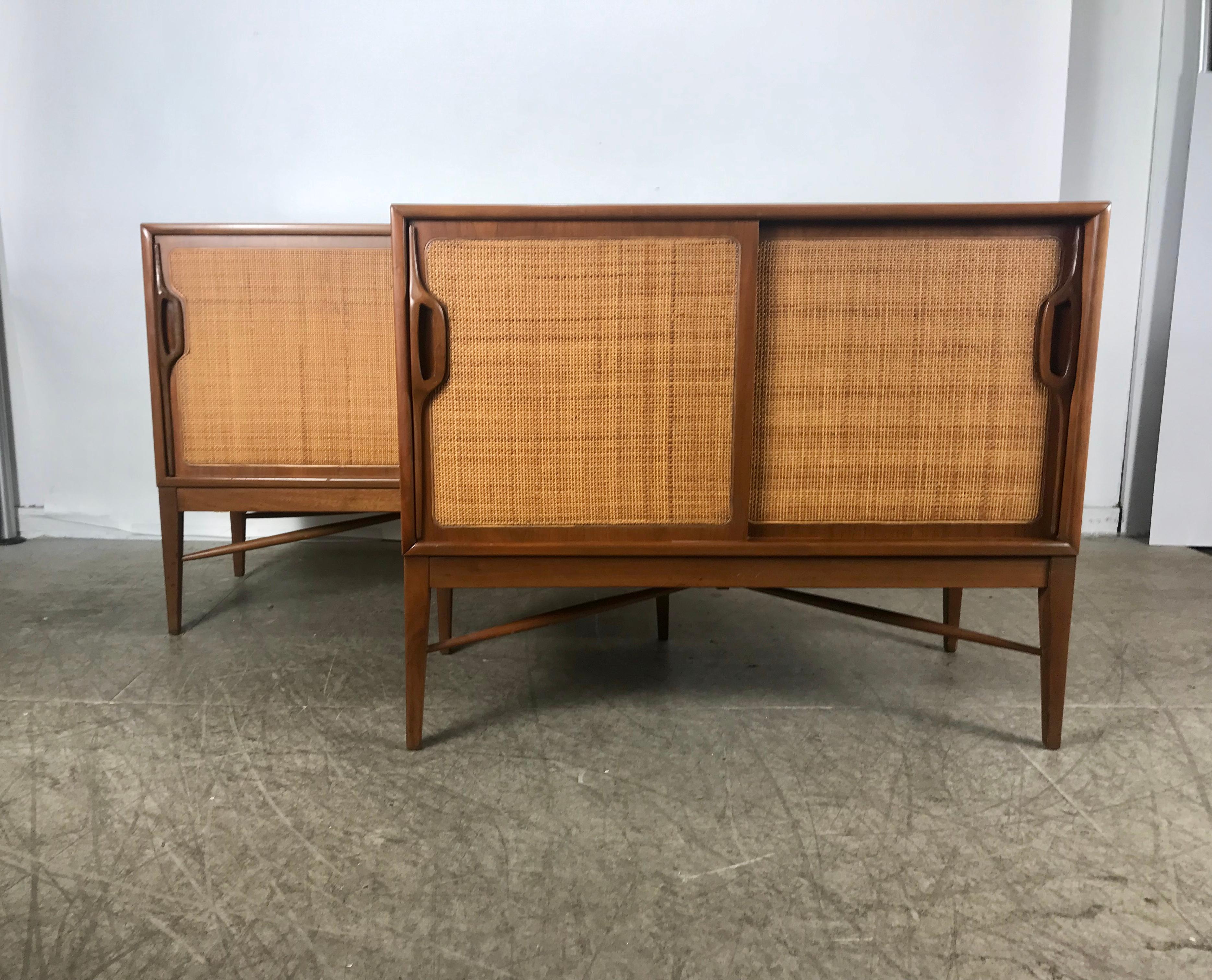 Pair of modernist American Danish walnut sliding caned door cabinets. Classic Mid-Century Modern design, unusual leg stretcher design, sculpted walnut hand pulls, hand delivery avail to New York City or anywhere en route from Buffao ny.