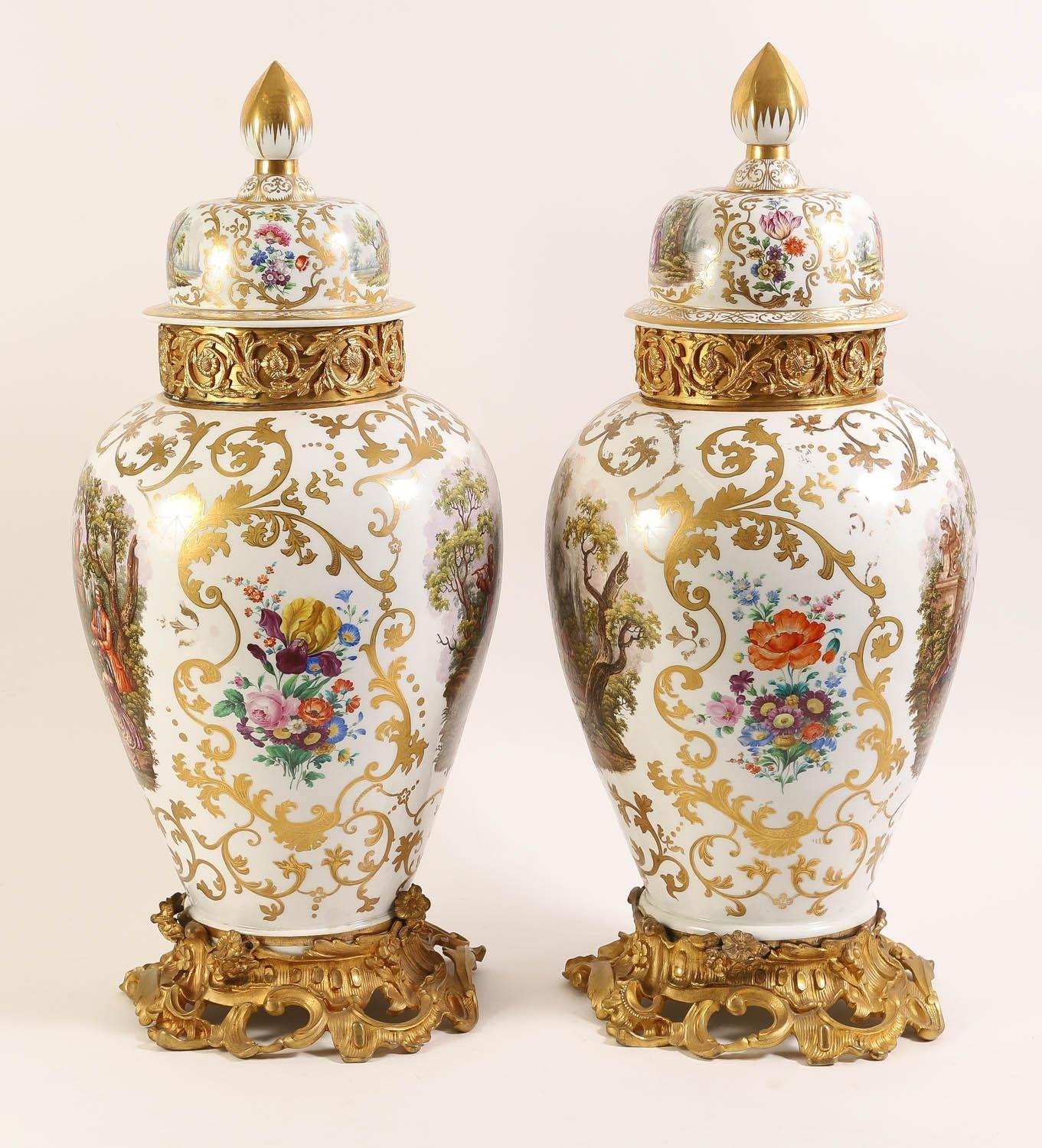 Paire de vases monumentaux anciens (19e siècle) en porcelaine avec couvercles et montures en bronze doré.  Les corps et les couvercles sont peints à la manière de Watteau, avec des groupes de fleurs et des rinceaux de feuillage peints en doré sur