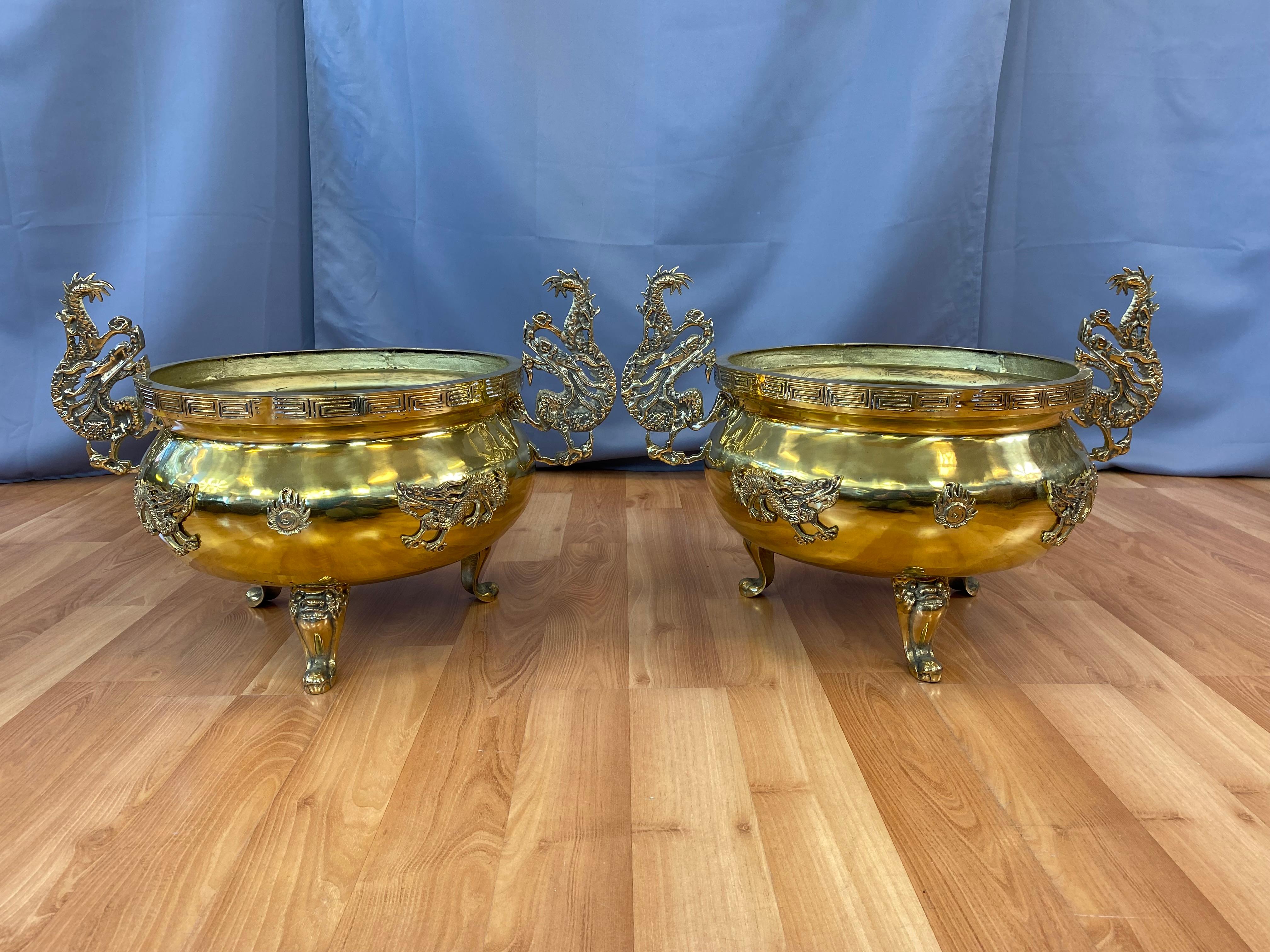 A pair of Monumental Brass Chinese style jardinières. 
Chinese styling throughout, from the dragons on the feet and sides, a sun on front to the handles.
Main body has a extra layer of Brass on the bottom, which gives more support.

Has no