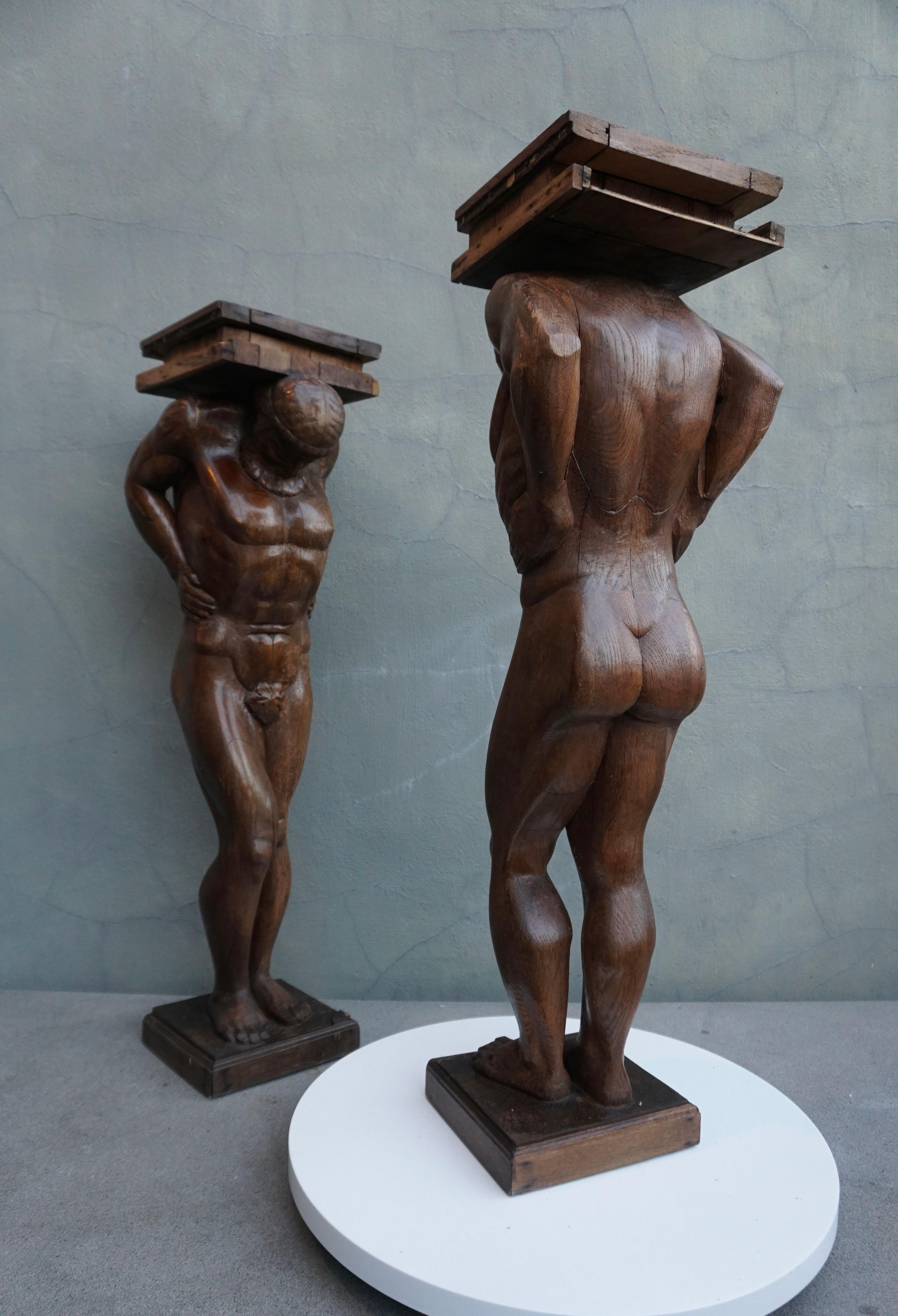 Two carved of oak columns or pedestals, each of a muscular male figure, representing Atlas or Hercules, the head inclined forward and supporting as well with the shoulders a square platform.

These stunning and beautifully crafted wooden sculptures