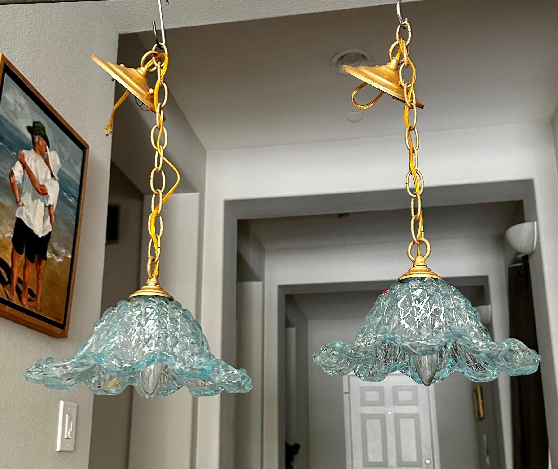 Pair Italian murano smaller scale tulip shape hand blown blue teal glass ceiling light pendants. The metal hardware is gilt finish including chain and ceiling cap —see close ups for how finish looks. 
Each fixture uses single candelabra size E12
