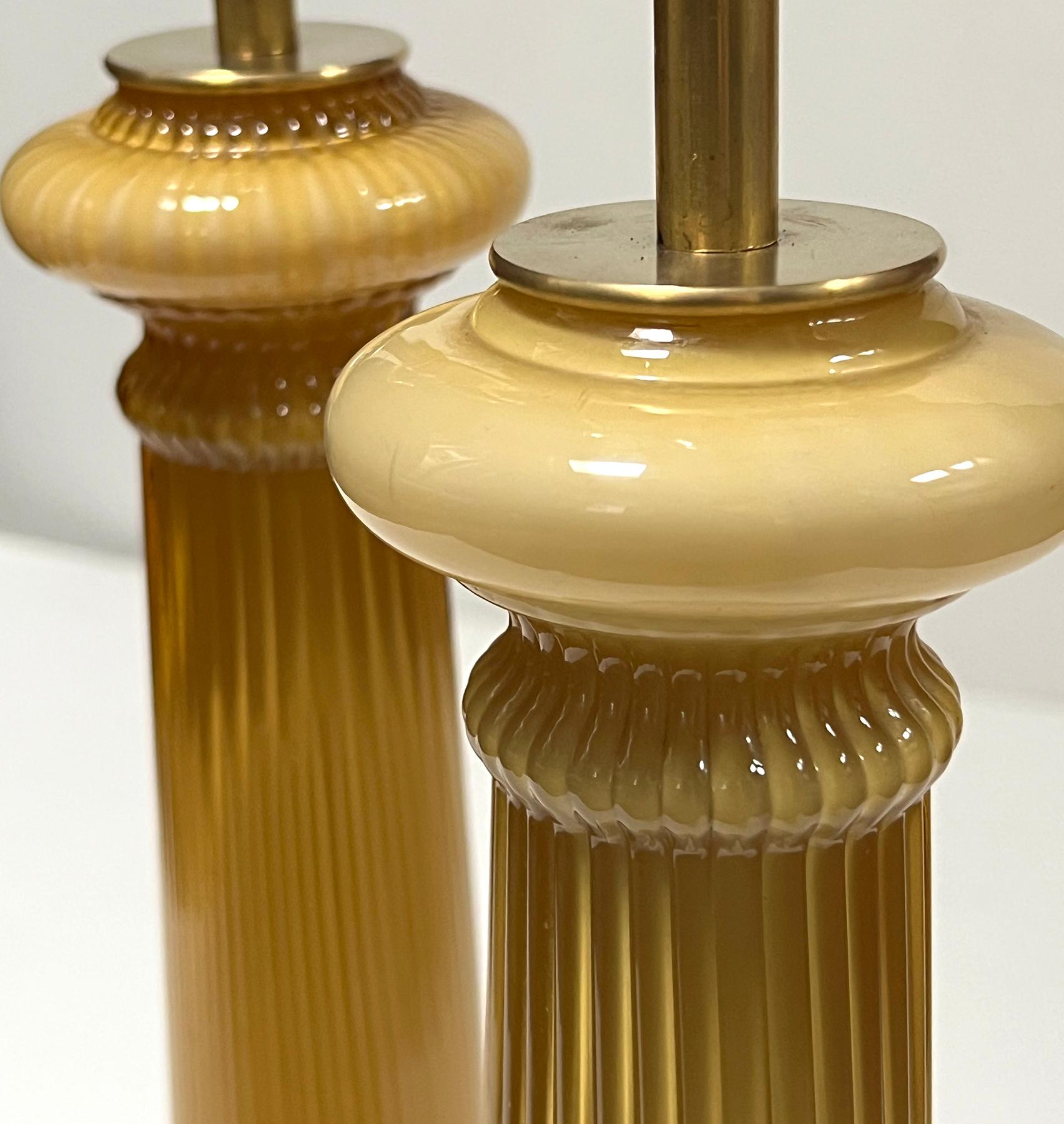 attributed to Warren Kessler Lamps, New York est. 1939; each hand-blown columnar lamp of baluster-form with reeded shaft above a bulbous mid-section over a cylindrical pedestal and splayed foot; all resting on a gold painted metal base; each in a