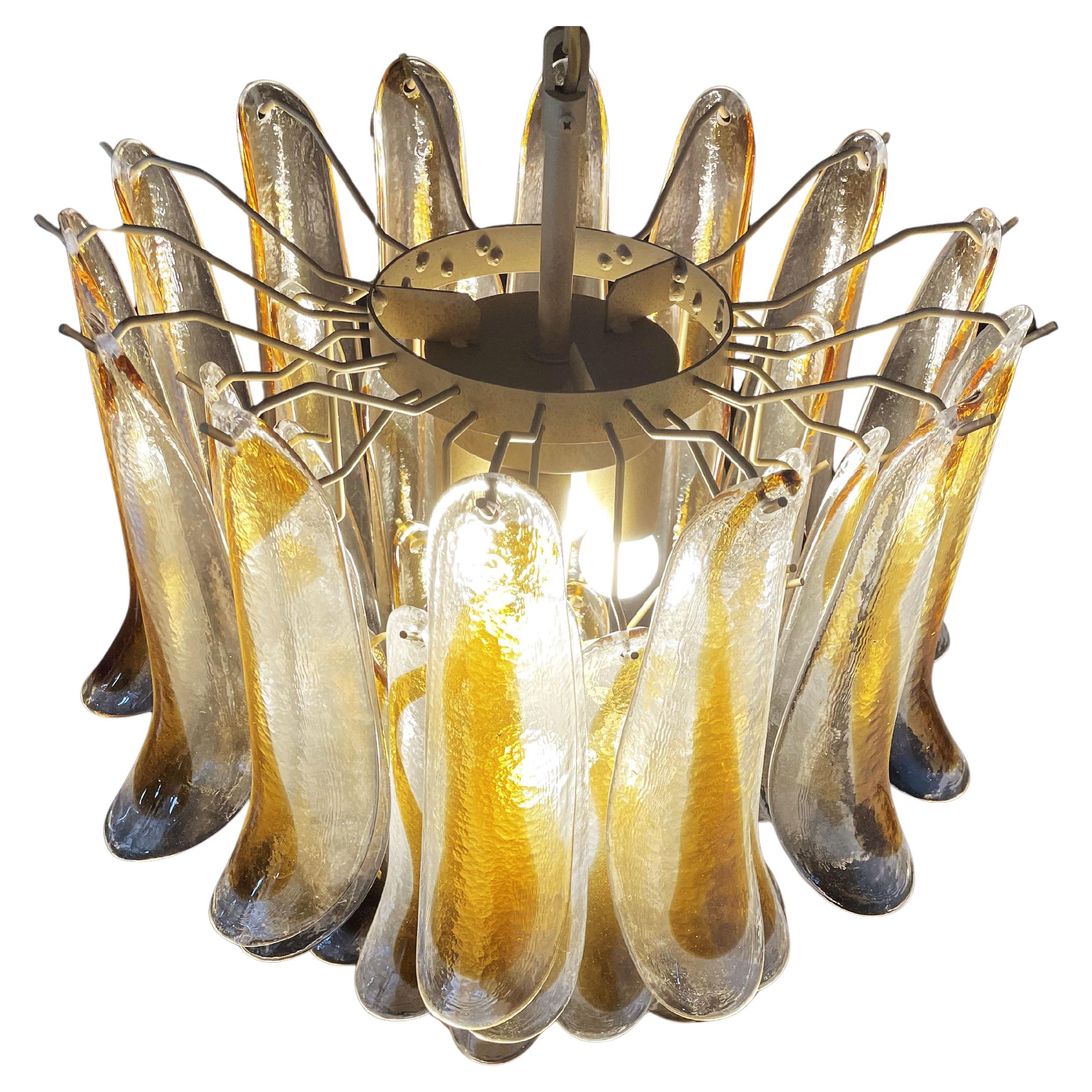 Coppia di lampadari vintage italiani di Murano, ciascuno composto da 41 petali di vetro (trasparente e ambra) in una cornice di metallo verniciato oro. Periodo: fine del XX secolo
Dimensioni: 46 pollici (117 cm) di altezza con catena; 25,60 pollici