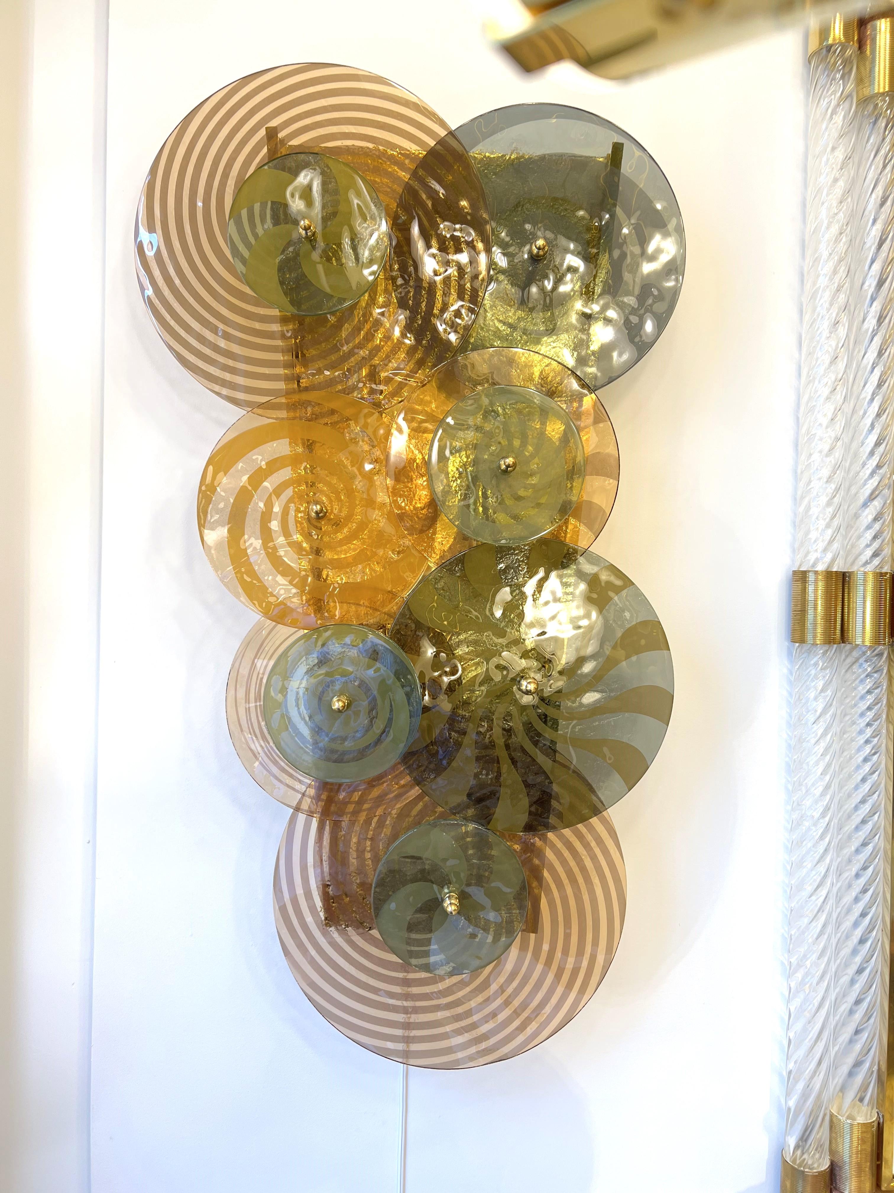 Rare and one-of-a-kind pair of Murano Glass Spiral Discs and Brass Sconces. Hand-casted Murano glass discs, both spiraled and ridged, in various diameters and in hues of sage green, smoked taupe, amber and muted blush pink adorn the front of these