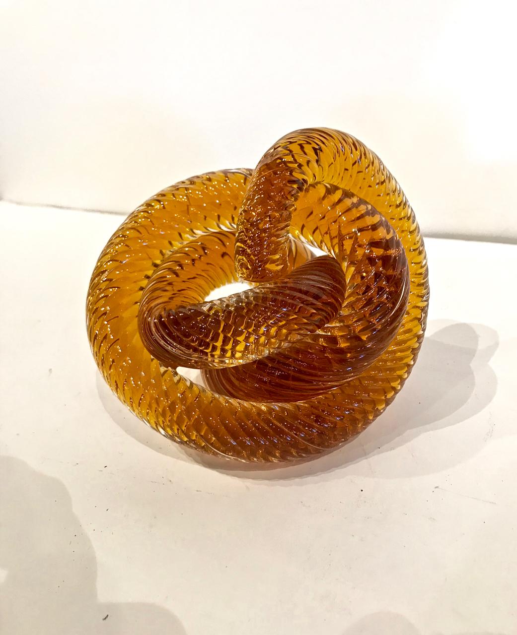 This is a highly decorative pair of Murano glass knots attributed to to Zanetti. Both knots are moth blown in a deep amber or root beer glass tone. The ribbed surface attracts and reflects light--making this pair great eye-catchers.