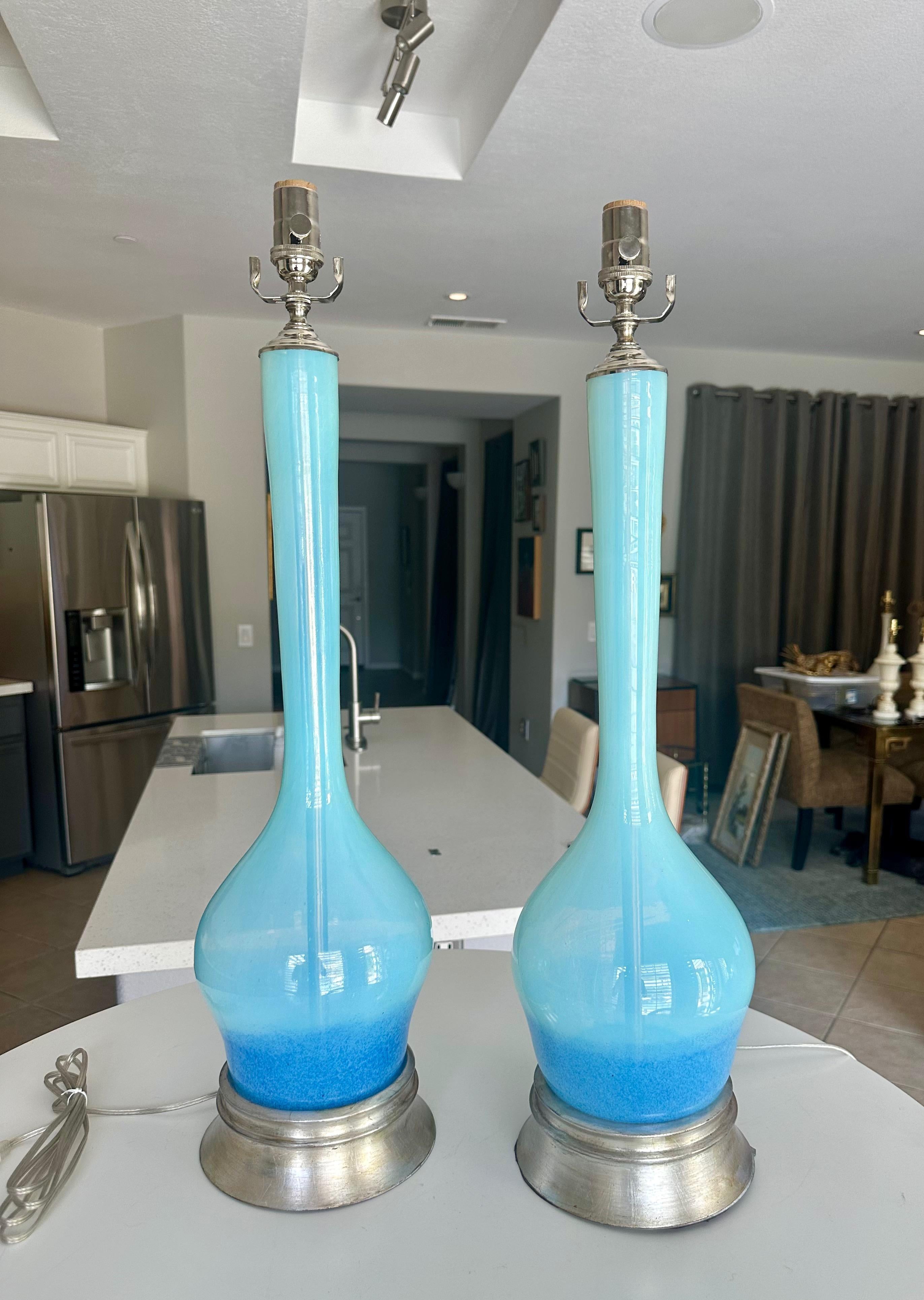 Pair mid century long neck Murano Italian light transparent blue glass (with darker applied blue color at base) table lamps. Mounted on a silver gilt metal bases. Newly wired with nickel-plated fittings, including a 3 way sockets and and silver