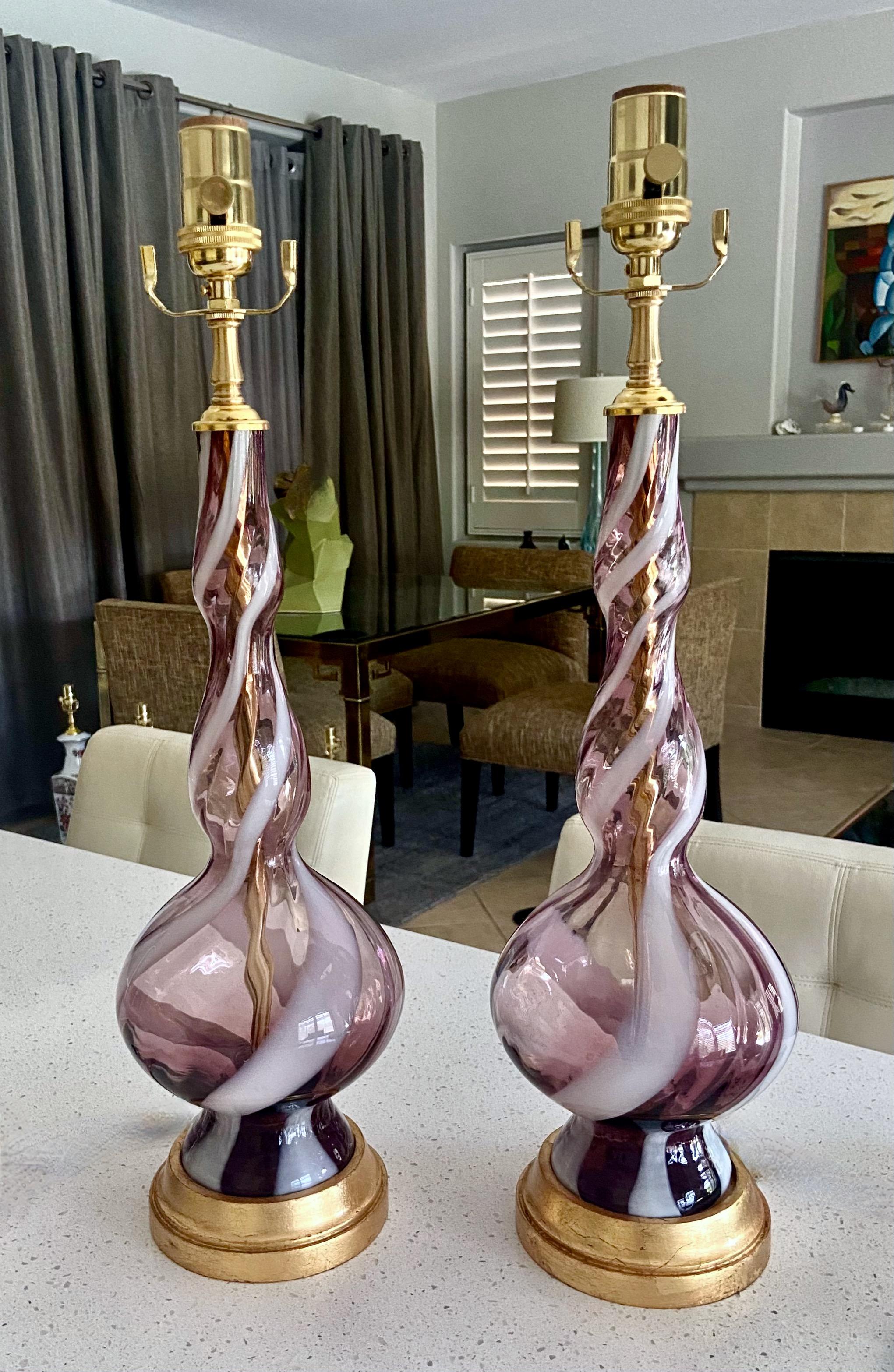 Pair of Murano hand blown purple and white swirl stripe table lamps on giltwood bases. The lamps are lighter overall weight with slender/smaller glass bodies, perfect for smaller room spaces. Newly wired with 3-way brass sockets, new fittings and
