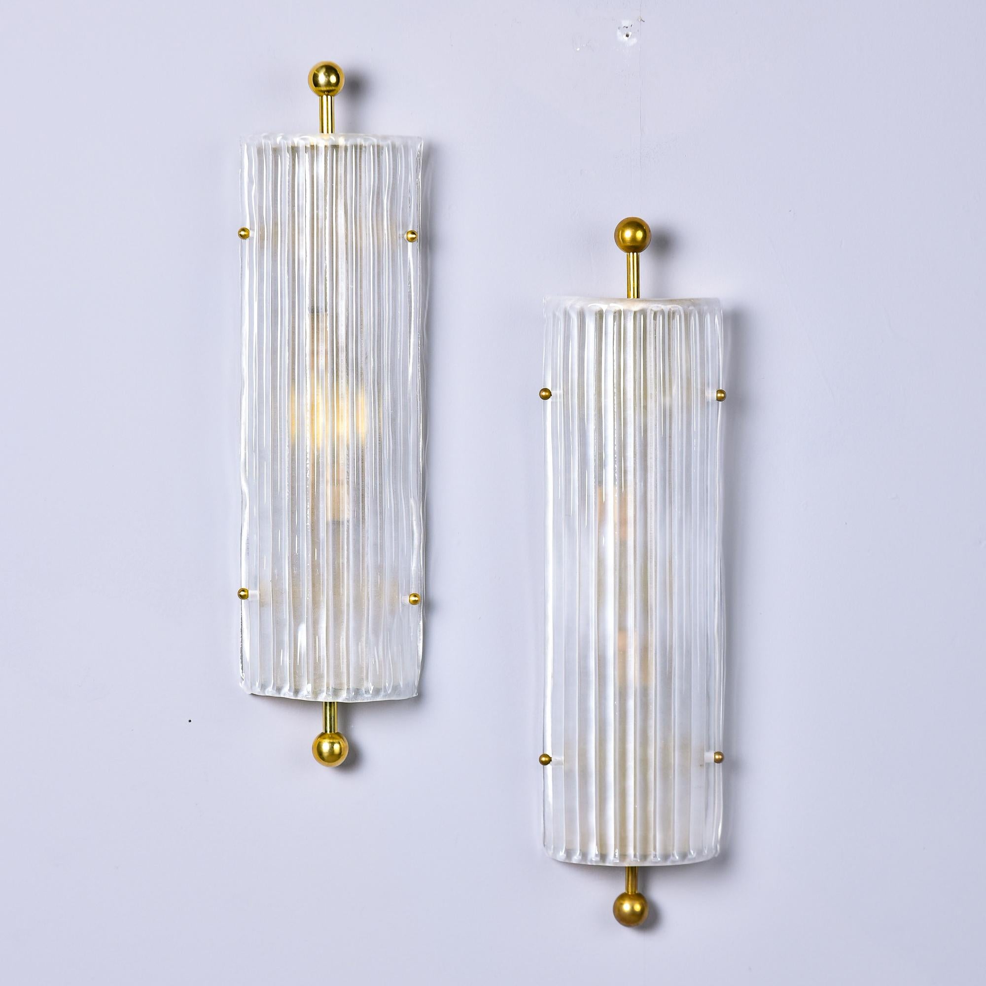 New and made in Italy, these sconces are made of heavy, clear ribbed-texture Murano glass with polished brass hardware. They are just over 22” high and can be mounted vertically or horizontally. Each sconce has two candelabra sized sockets. Sold and
