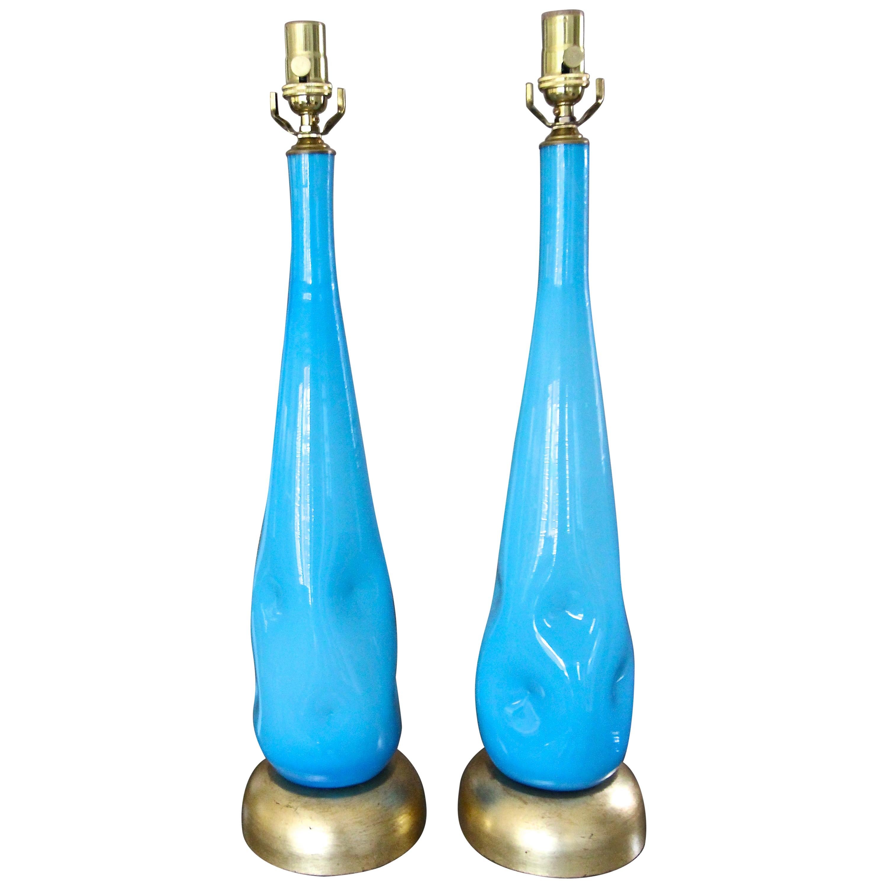 Pair of Italian hand blown Murano tall sky blue incased colored glass table lamps. The Mid-Century Modern organic glass design features random indented dimples, and rest on gold gilt metal bases. Newly wired for US with new 3-way sockets and brass