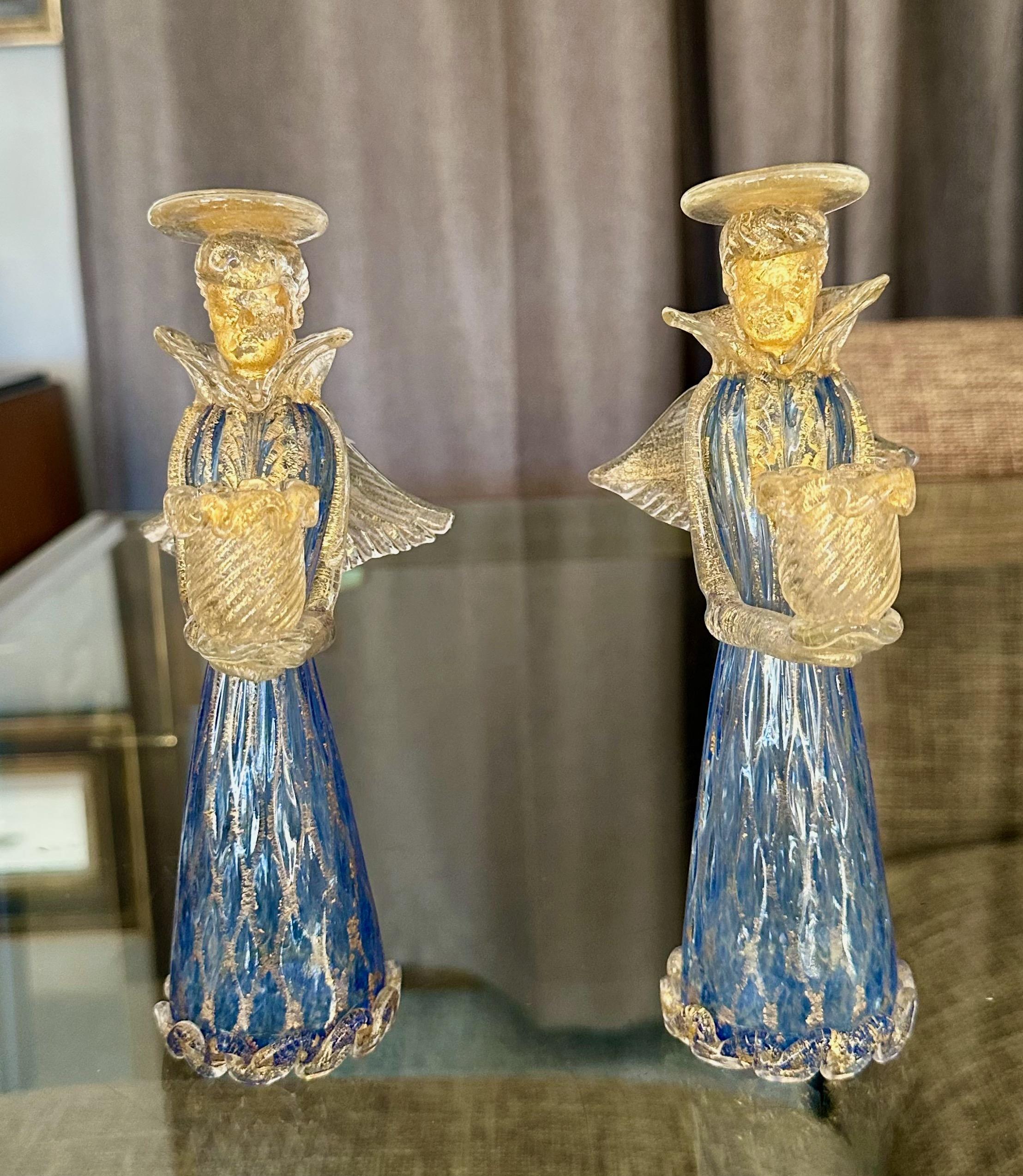 Pair of Murano Italian Venetian art glass Angel candleholder figurines. The color of the glass is combination blue and clear, with gold aventurine diamond pattern on their bottom dress portion, plus gold inclusions throughout.  
