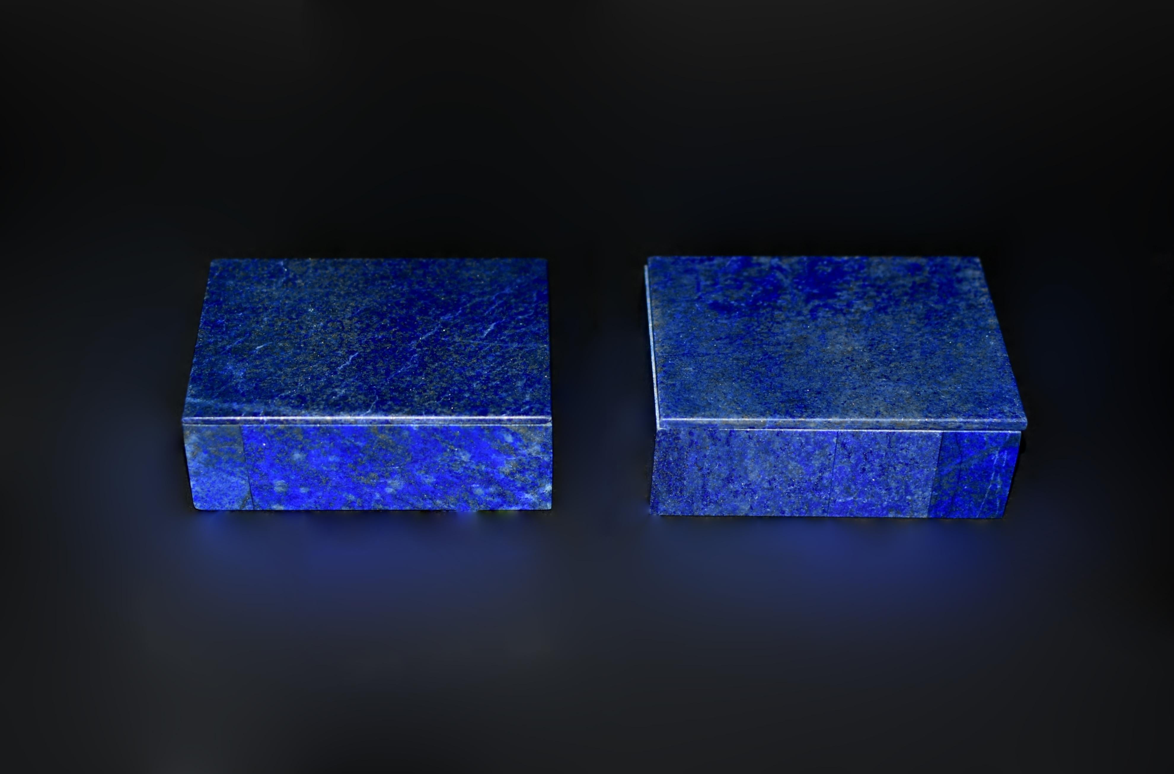 This beautiful pair of lapis boxes, crafted from fine natural lapis lazuli from the depths of Afghanistan, radiates a regal splendor with its deep, saturated royal blue hue. Each box is distinguished by a rare single-board lapis slab on the cover,
