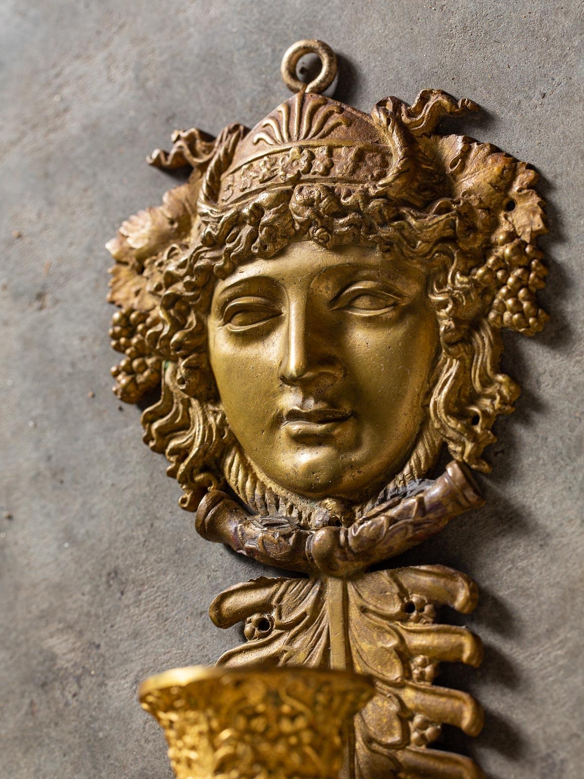 A pair of neoclassical antique French gilt bronze sconces Napoleon III period circa 1870. This pair of three arm French sconces feature a bold portrait head of Bacchus Dionysus (look at the entwined grape clusters and grape leaves entwined in the