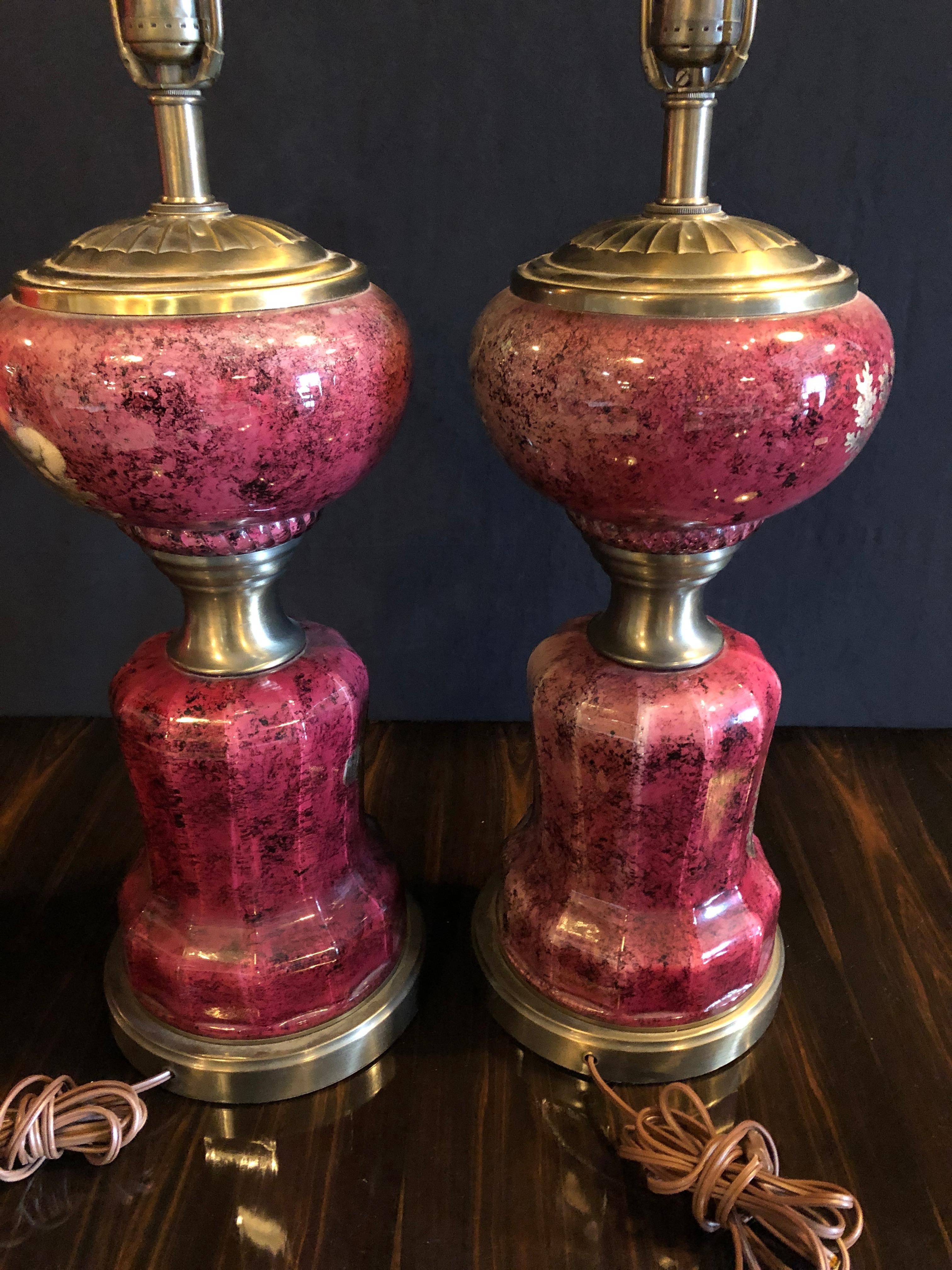 Pair of neoclassical cranberry glass decoupage cherub decorated table lamps. The vase measures 16 inches in height. Each lamp with finely decorated babies on a cranberry background.