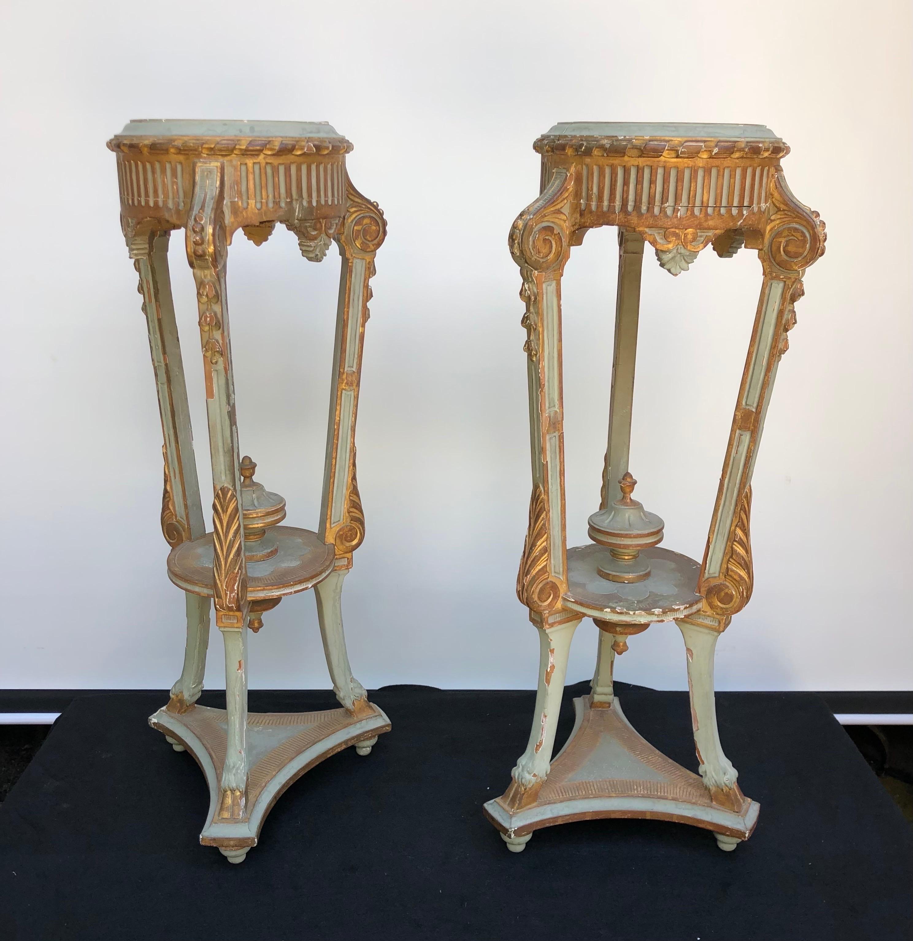 Pair Neoclassical Italian Painted Parcel-Gilt Torchieres / Pedestals made in the late 18th century. This pair of classical tripartite pedestals are finely carved having a fluted apron, foliage, urns, and hoof feet all emphasized with gilt. These