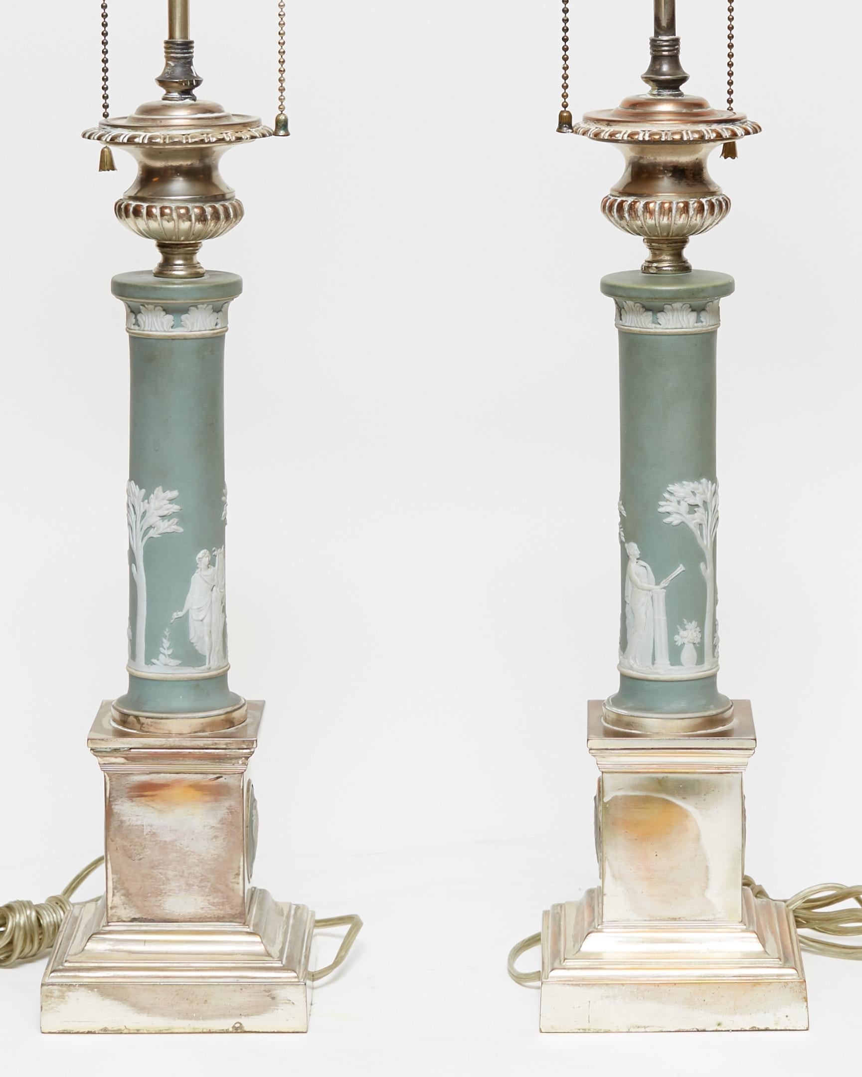 Pair of table lamps in the neoclassical style, with standards of Jasperware porcelain in Roman column form, with square silver gilded bases with classical Jasperware medallions. Possibly from Wedgwood.