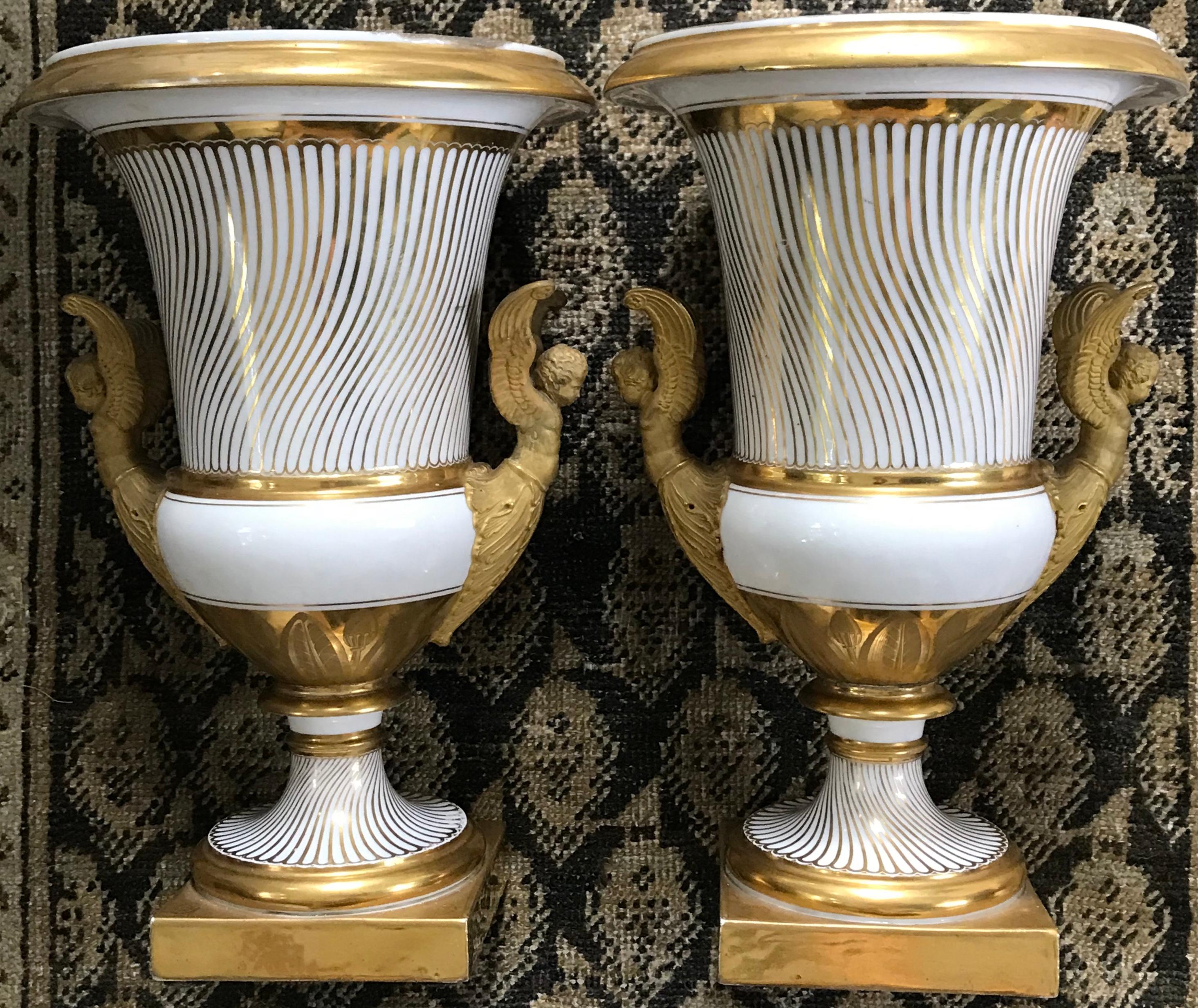 Pair neoclassical Paris Porcelain gilt vases. Exceptional pair of large white and gilt painted campana form urns with strigilated patterning on body down to gilt banded white base above gilt patterned olive and leaf banding with further strigilation