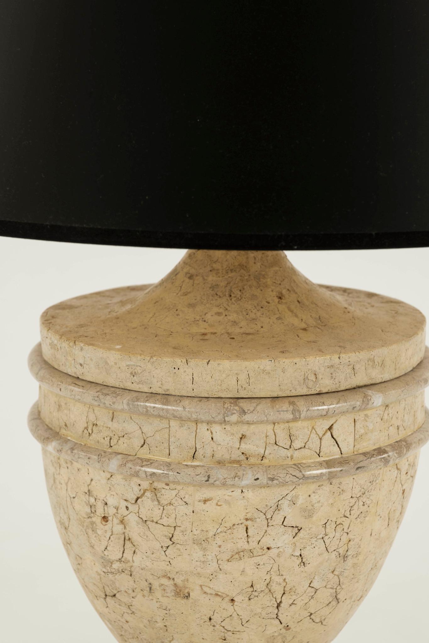 20th century neoclassical style stone table lamps. Handsome and stately beige urn on plinth base lamps with black shades.
