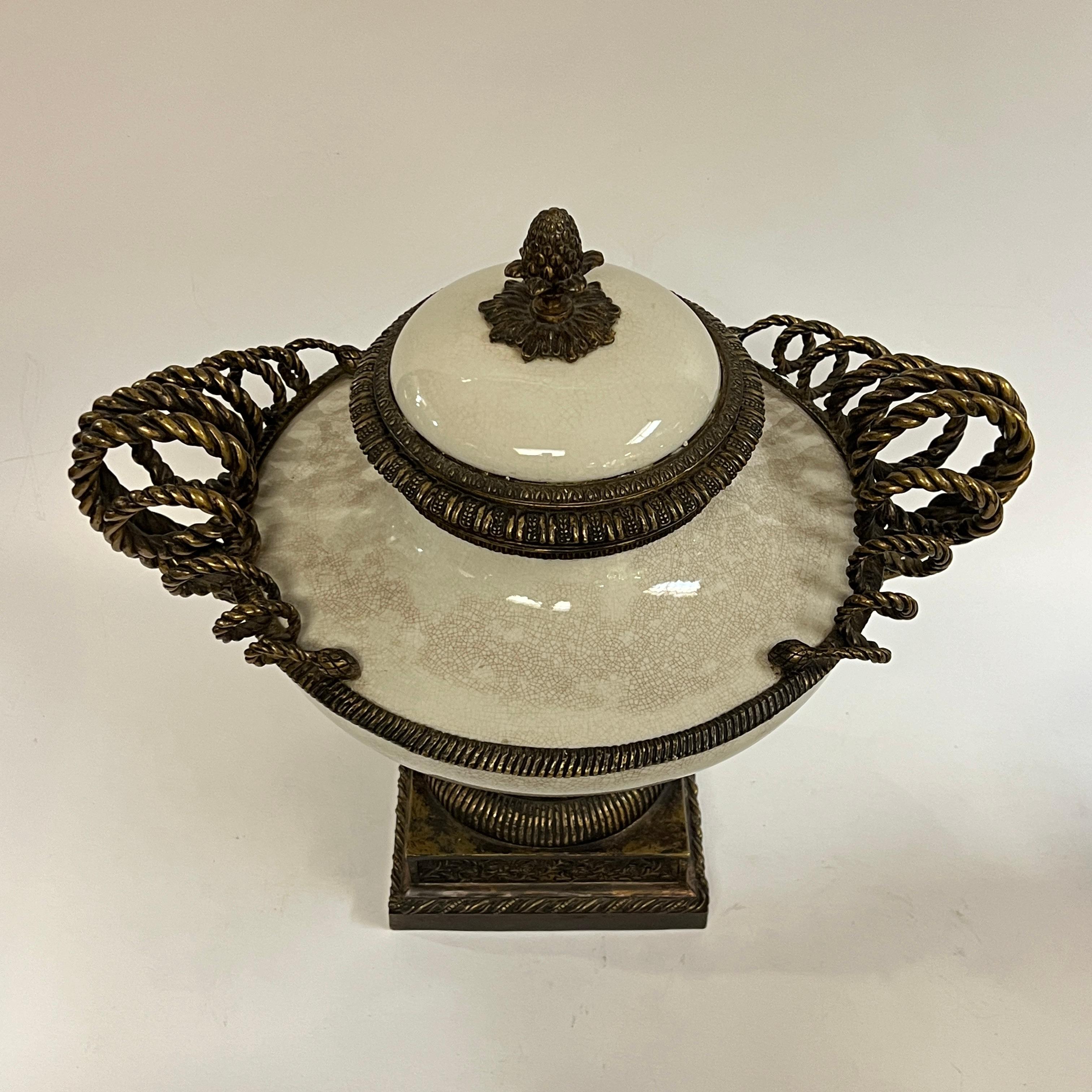 Coppia di grandi dimensioni  urne in ceramica con smalto beige crepato e montature in bronzo patinato con motivi neoclassici, tra cui elaborate maniglie a volute, tralci floreali, acanti e coperchi con terminali ad ananas.  Apparentemente non