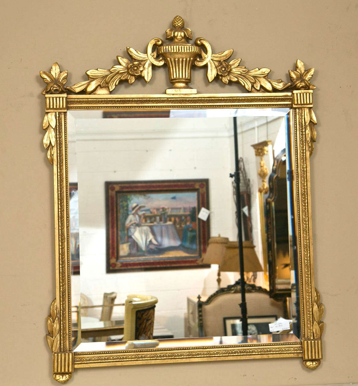 Pair of neoclassical style giltwood console or wall mirrors, the square looking beveled glass surmounted in the giltwood frame, the top decorated with an urn crest and foliage.