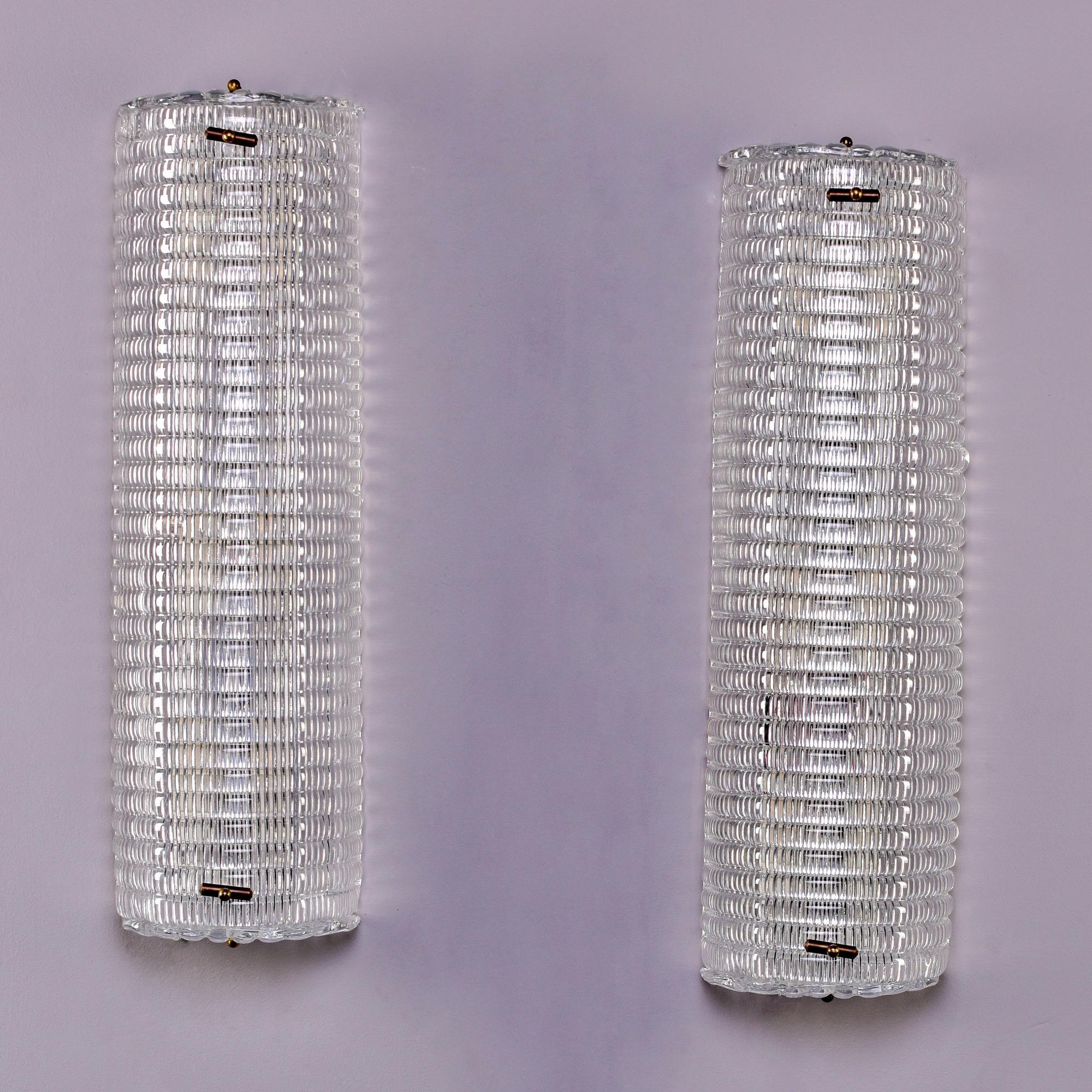 New and made in Italy of Murano glass elements, these sconces consist of thick, clear glass that has a ribbed texture on the inside surface. Each sconce is just over two feet tall (or wide - depending on how they are oriented on the wall) and has