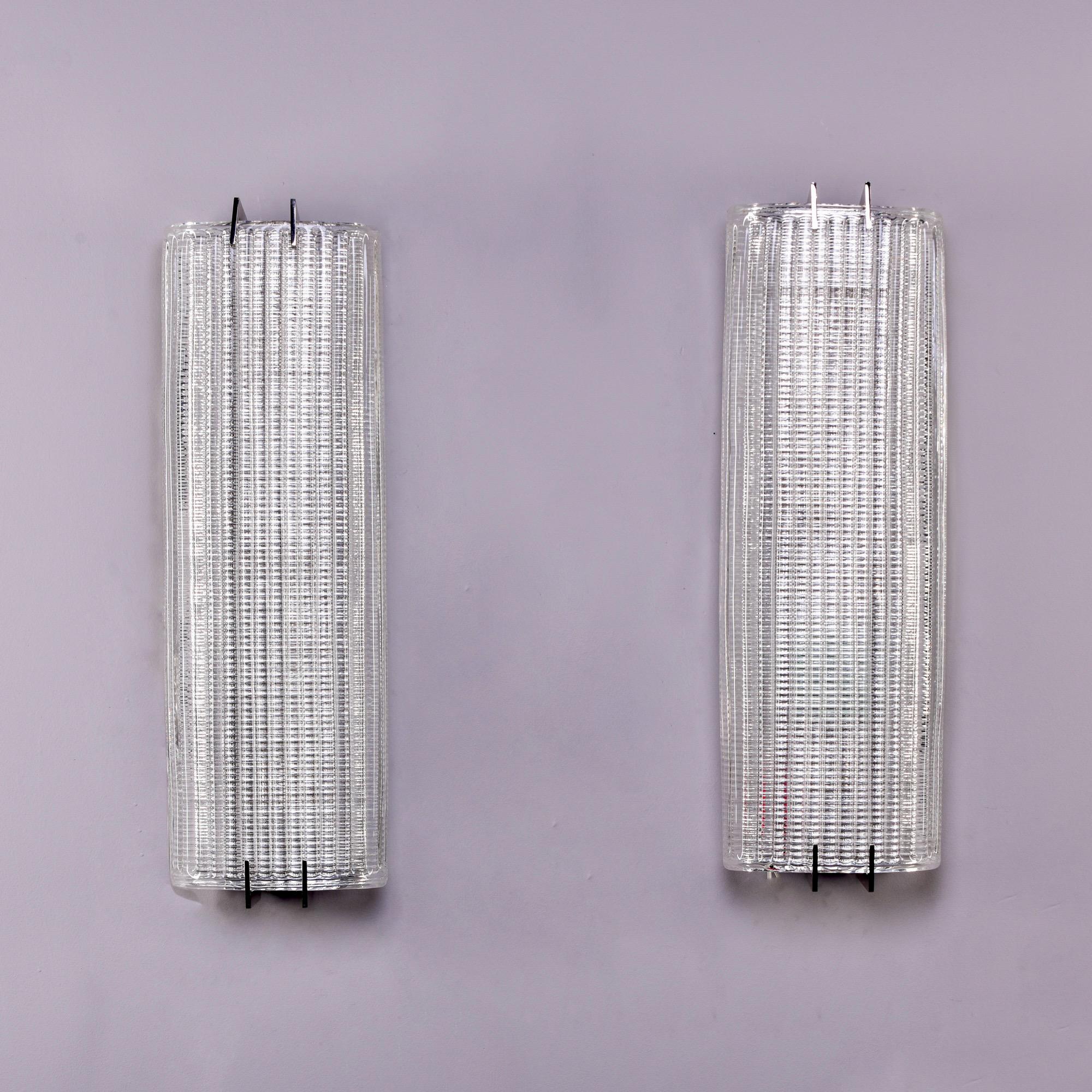 New sconces of heavy, clear textured and ribbed Murano glass with polished chrome hardware are over 25” tall. Can be mounted vertically or horizontally. Each sconce has 4 sockets. Sold and priced as a pair. This style works well with mid century and