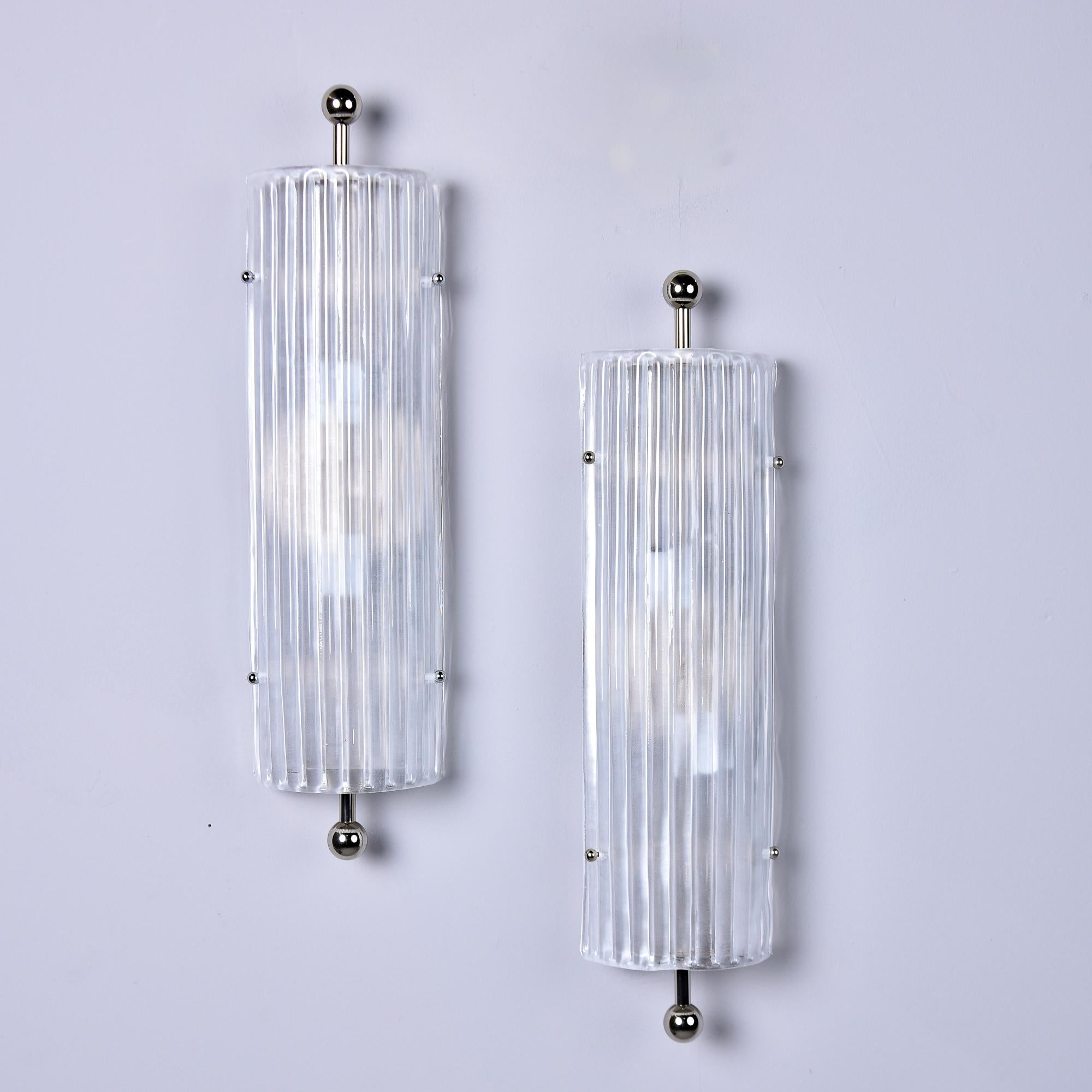 New and made for us in Italy, this pair of sconces feature tall thick Murano glass shades with a ridged surface and polished nickel hardware. Each sconce has two candelabra sockets. Sold and priced as a pair. 

Wired for US electrical standards.