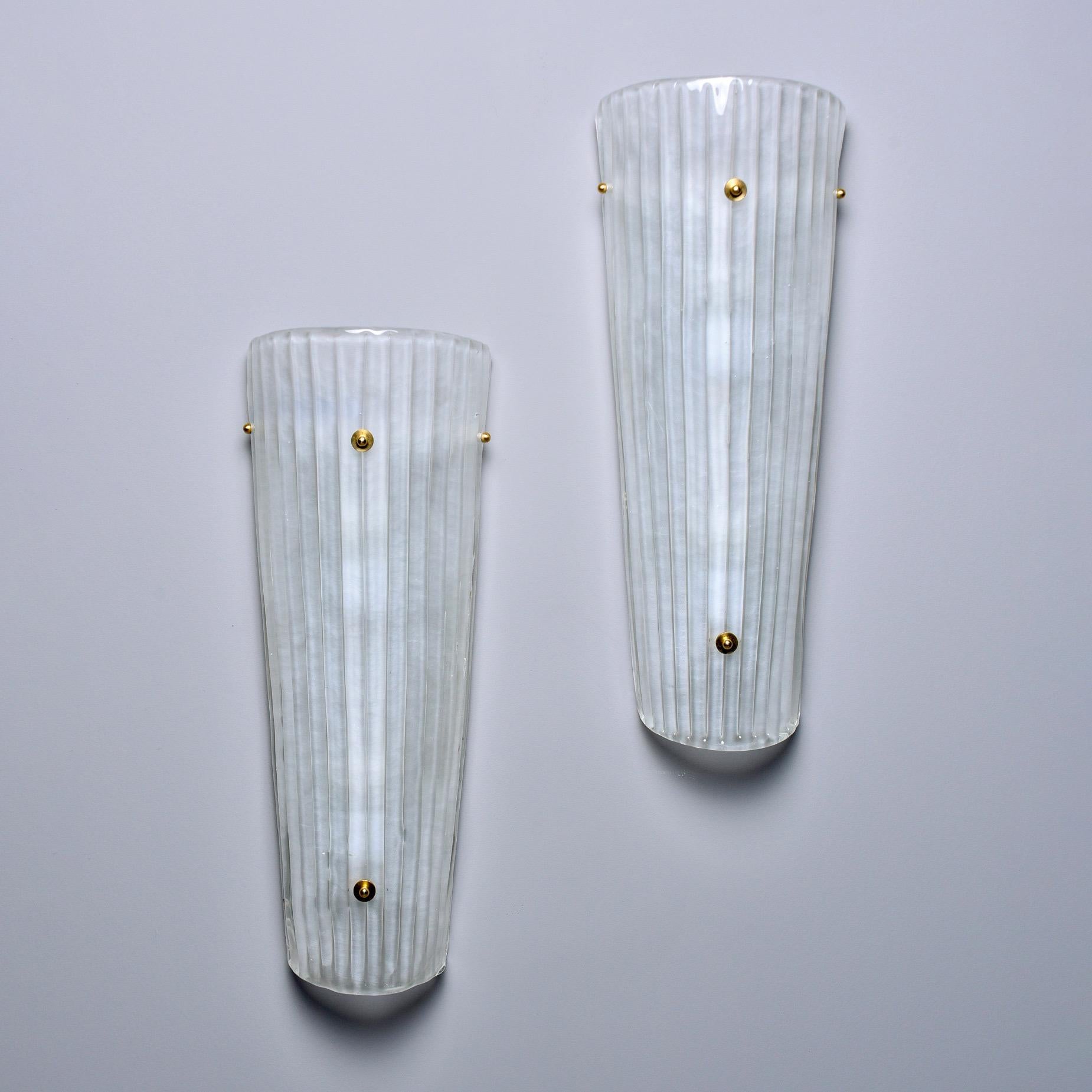 New and made for us in Italy, these sconces are nearly two feet tall. Made of white Murano glass, the shades have a ridged texture and brass hardware. Two standard sized socket for each sconce. Sold and priced as a pair.