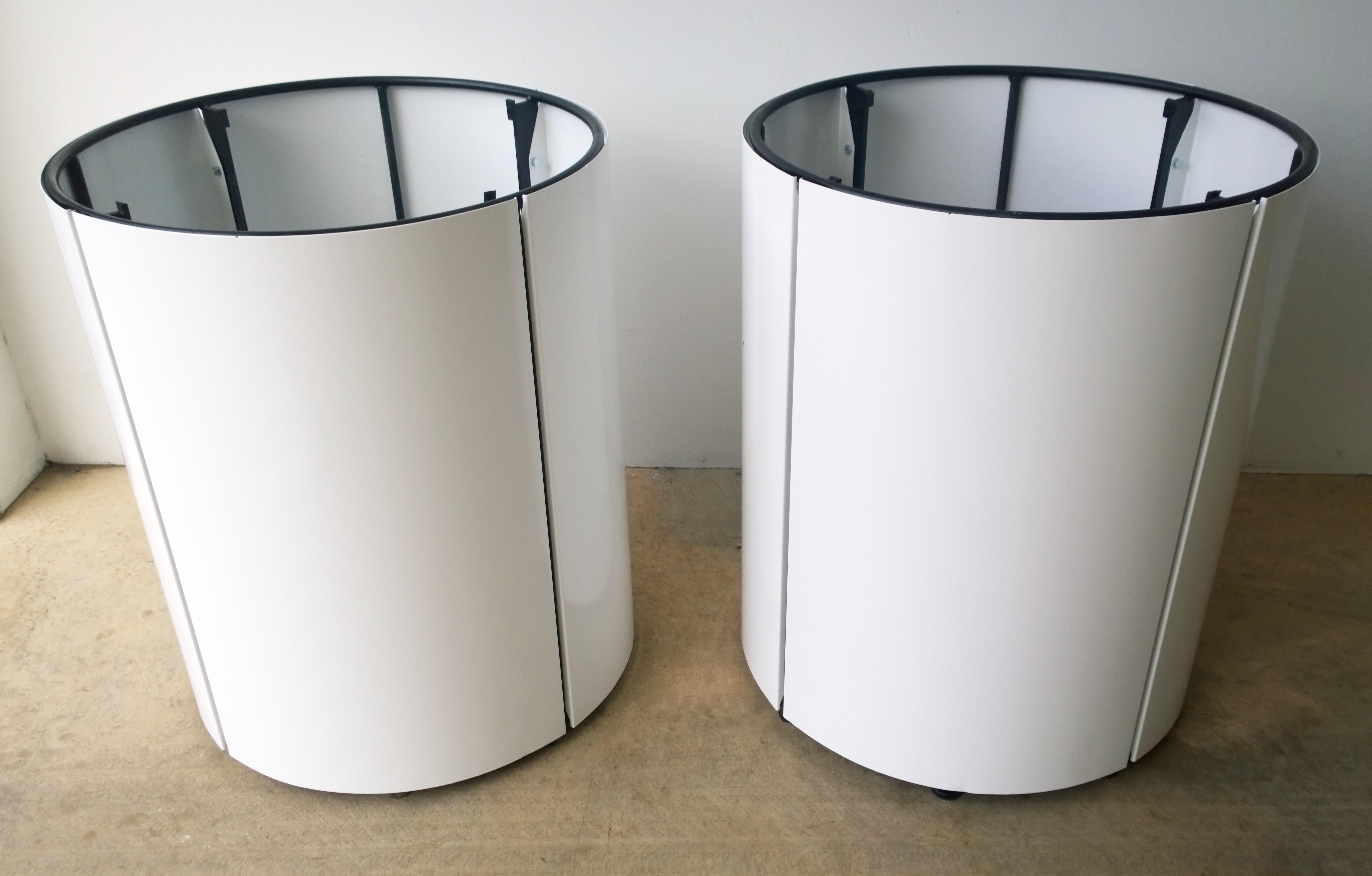 Offered is a Mid-Century Modern pair of newly powder-coated in white over metal panels attached to a black metal frame large planters. The planters each have a circular concrete block at the base for stabilization. The planters drain through the