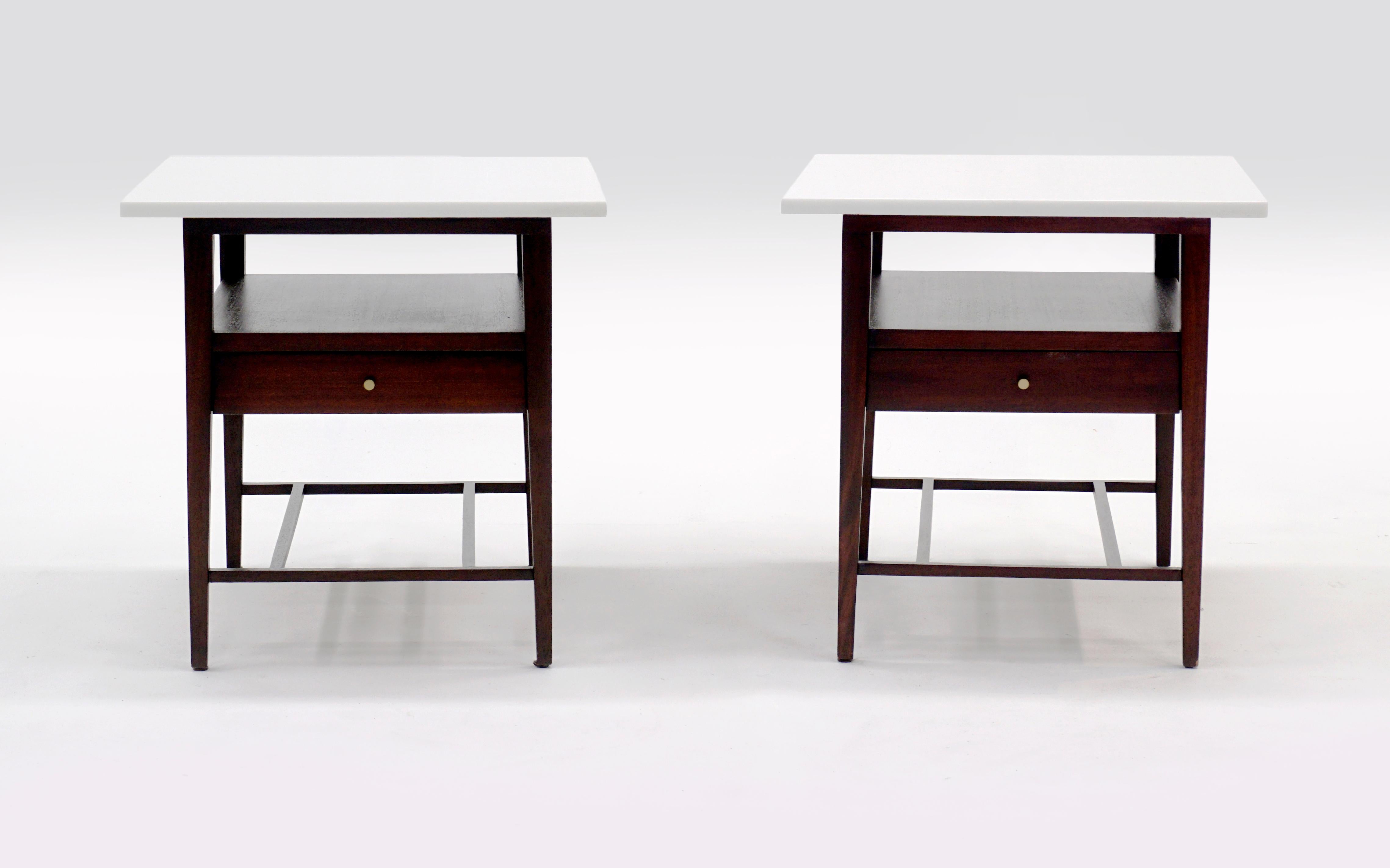 Pair of Paul McCobb nightstands / end tables with a single drawer, shelf, original brass pulls, and white Vitrolite tops. Both are in very good condition and were recently professionally refinished. These are part of McCobb's Irwin Collection for