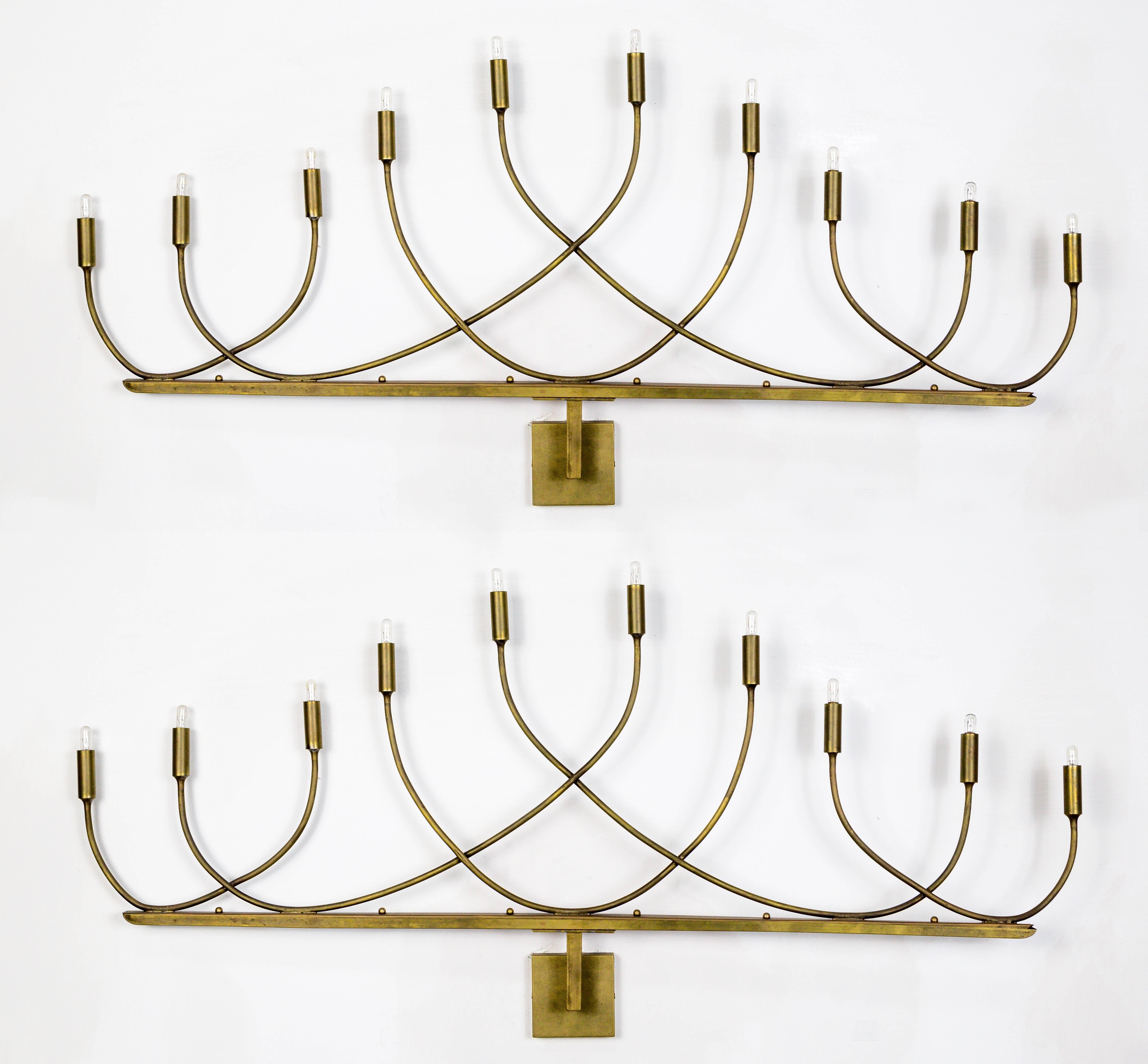 A streamlined, elegant, Hollywood Regency pair of monumental 10-light sconces; graceful arc to arms with softly rounded supports under brass candle sleeves. Back plate is 4