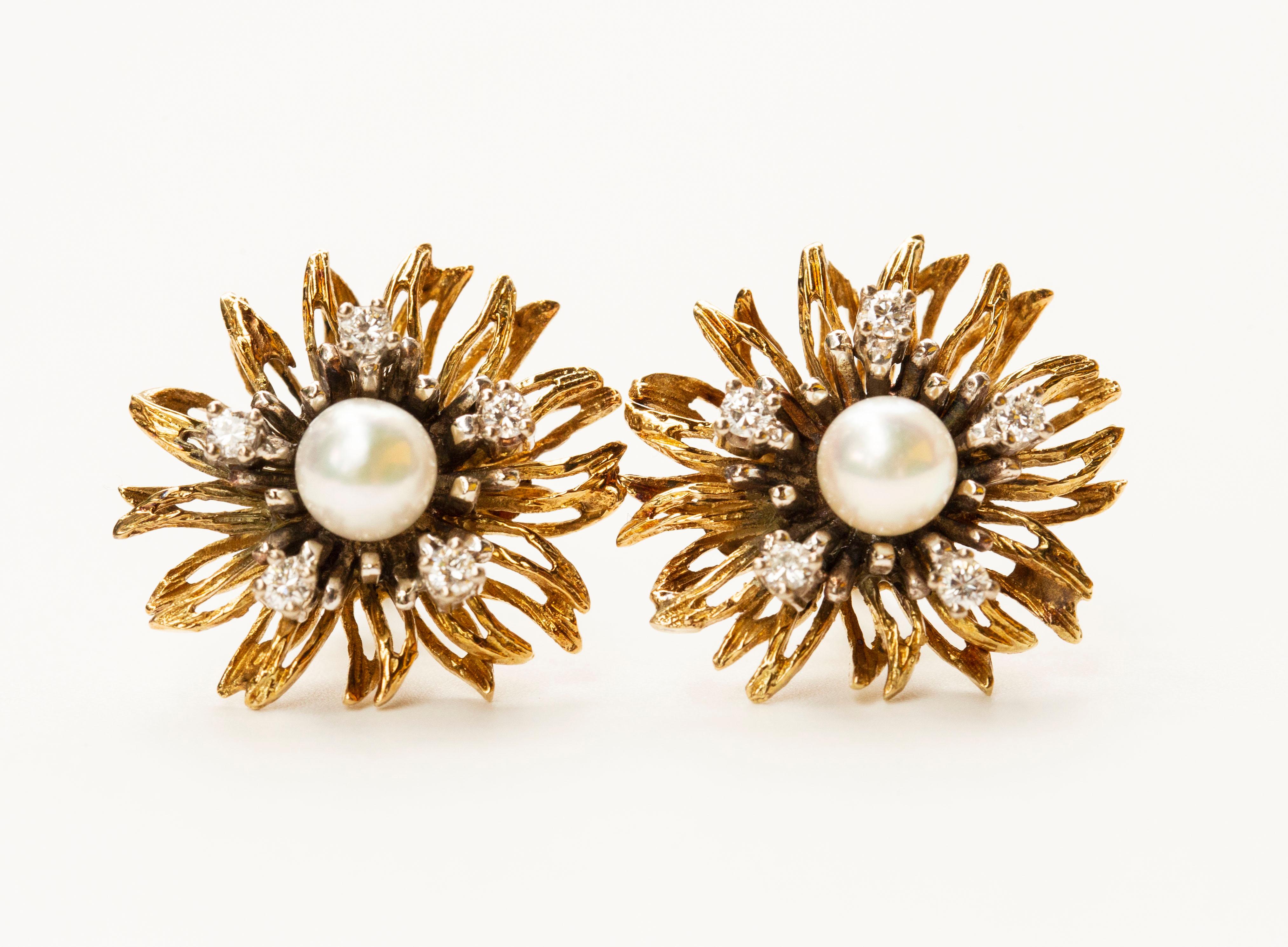 Une paire de boucles d'oreilles en or blanc et jaune bicolore 14 carats. Les boucles d'oreilles sont conçues sous la forme d'une fleur sertie d'une perle de culture au centre et entourée de cinq diamants taillés en brillant. Les boucles d'oreilles
