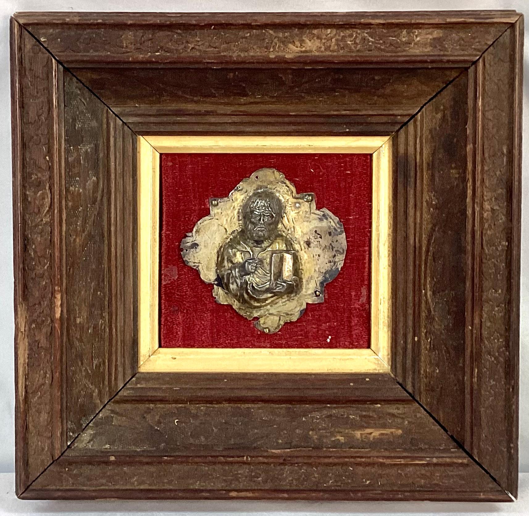 Pair of 17th Century Gilt silver framed saints. Silver saints are draped in period clothing and holding a book, against a red fabric background with gold trim. Square wooden frames have foliage carvings. Most likely originally used as mounts on