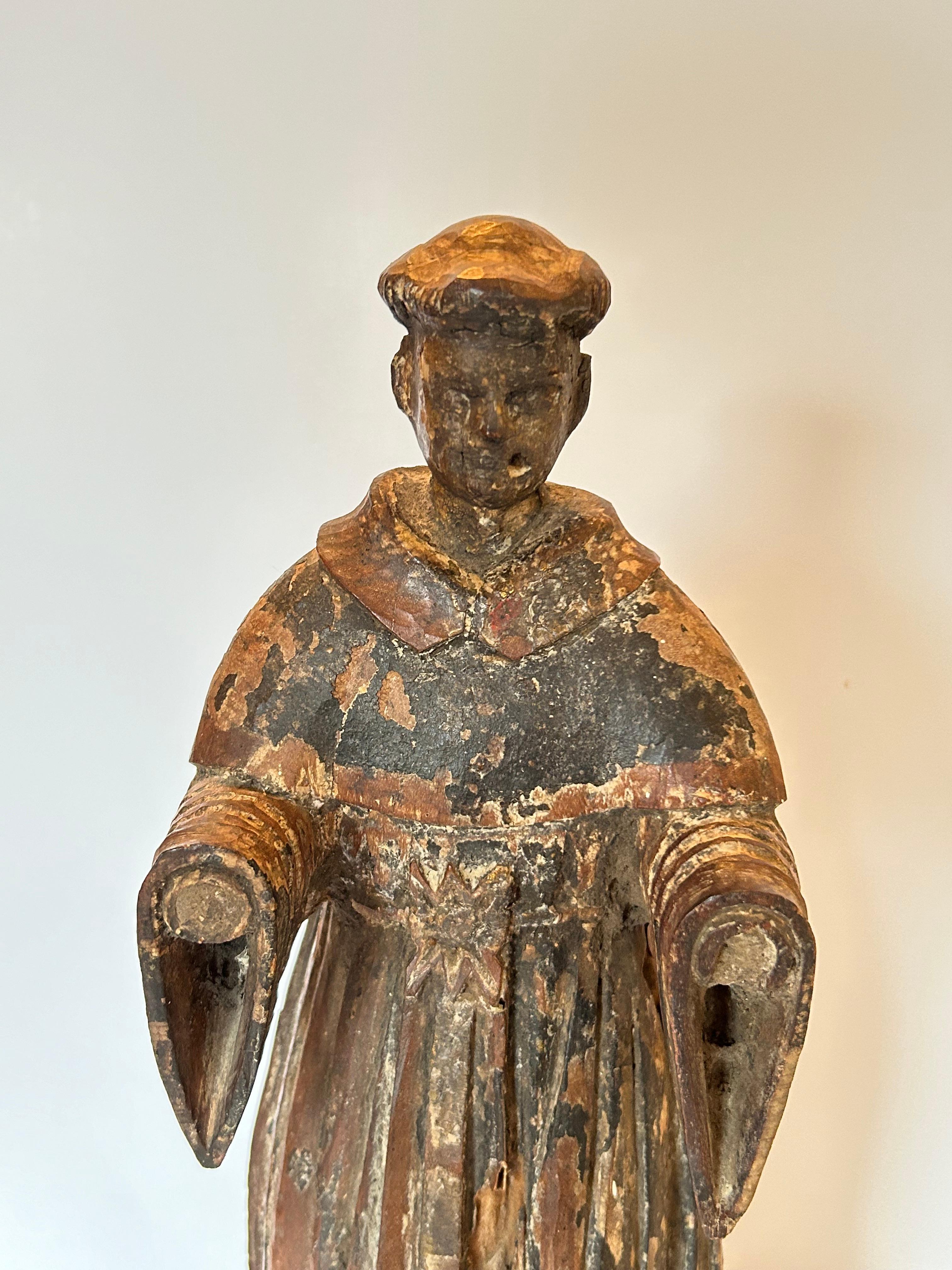 Two  Spanish Colonial antique Santos figures with polychrome and gilding, including a monk and a military saint figure. The monk is dressed in beautiful, dark robes with elaborate detailing to his belt. Although hands missing, his arms are