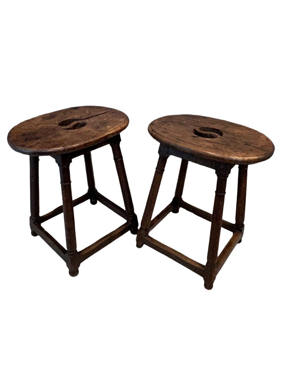 Pareja única de taburetes rústicos holandeses del siglo XVII (1600), tallados a mano, de forma ovalada, con asas centrales recortadas, elevados sobre cuatro patas torneadas unidas por camillas. Estos taburetes los utilizaban los artistas para pintar