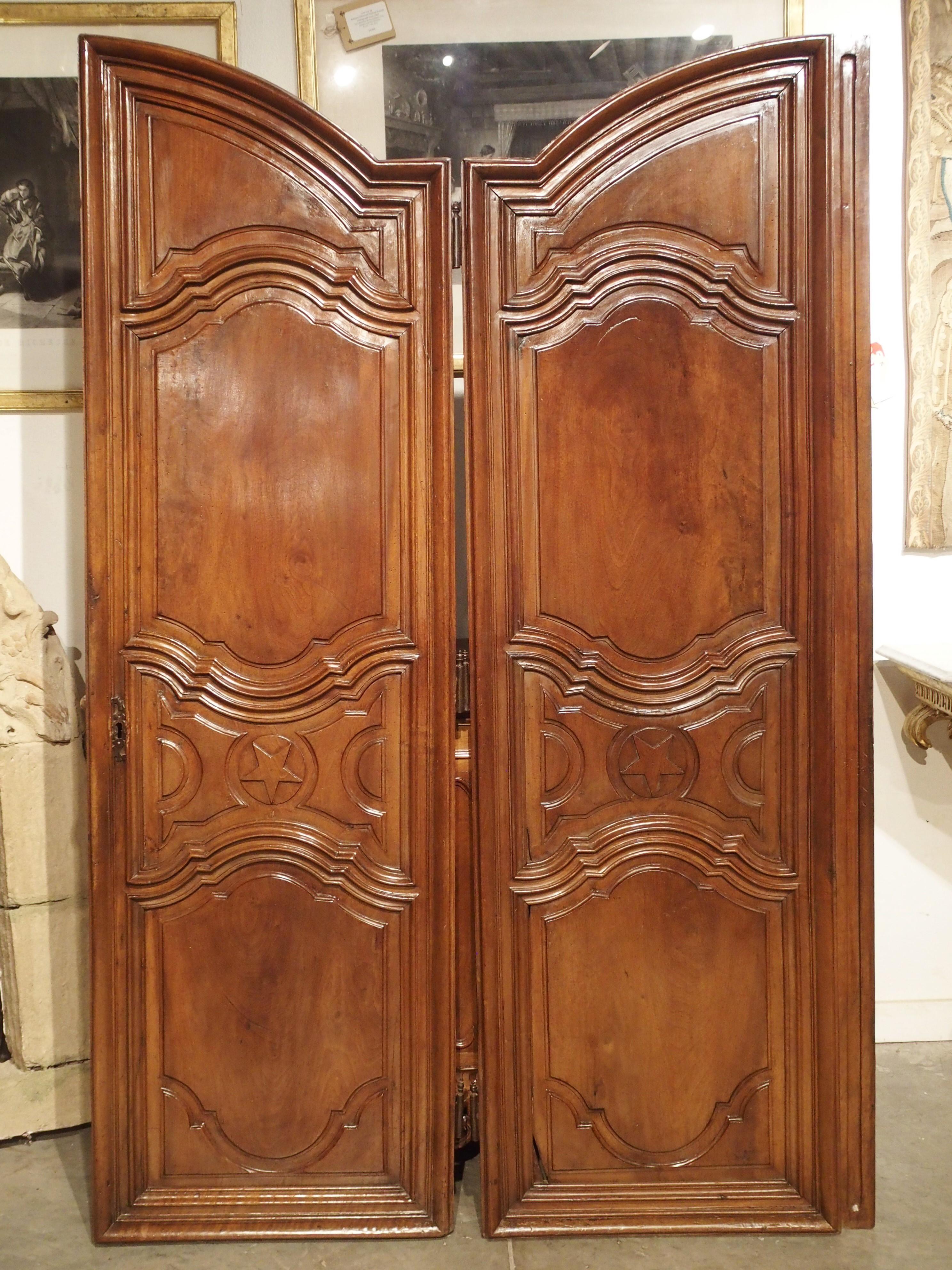 These lovely French doors are from the Ile-de-France region, and date to the late 1600s. Carved from sumptuous French walnut wood, these doors once belonged to a very large armoire. Each door is composed of 4 inset panels, which are framed by a