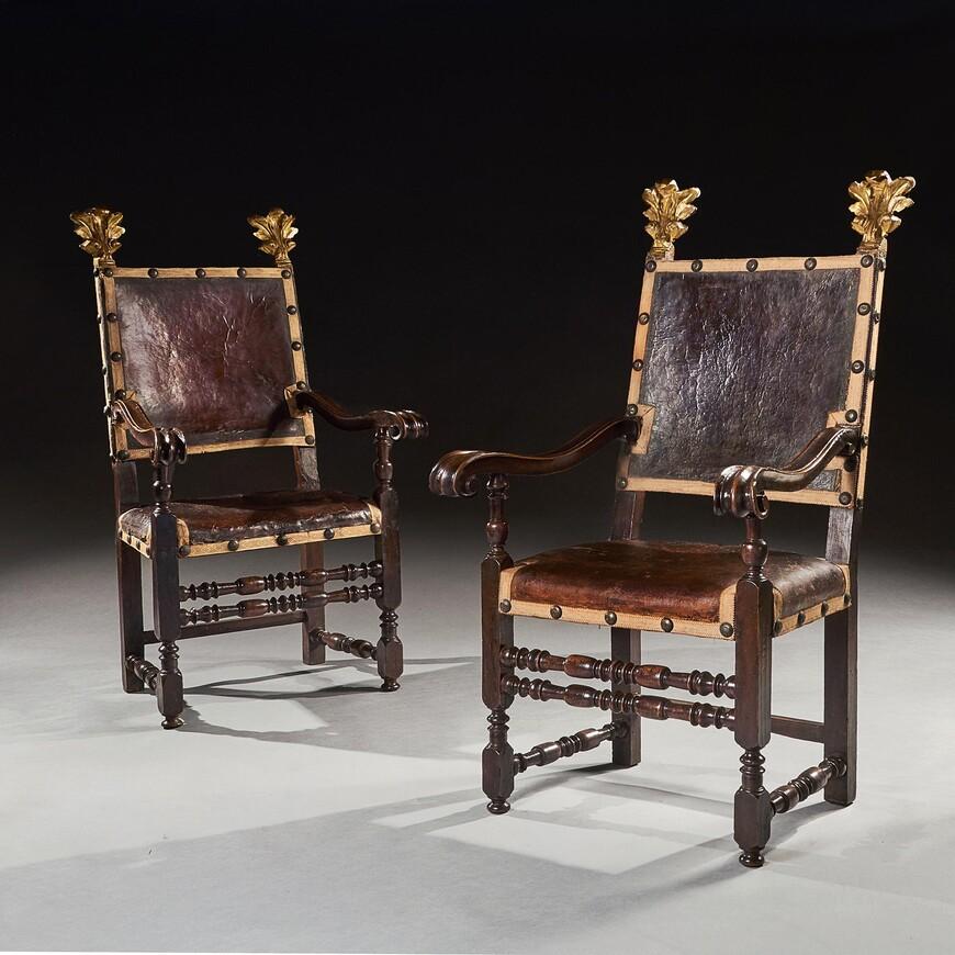 A fine pair of walnut Baroque Italian armchairs dating to the middle part of the 17th century retaining parts of extremely old leather seating.



Italian circa 1650-70.



The leathered and studded square backs with elaborate foliate-carved