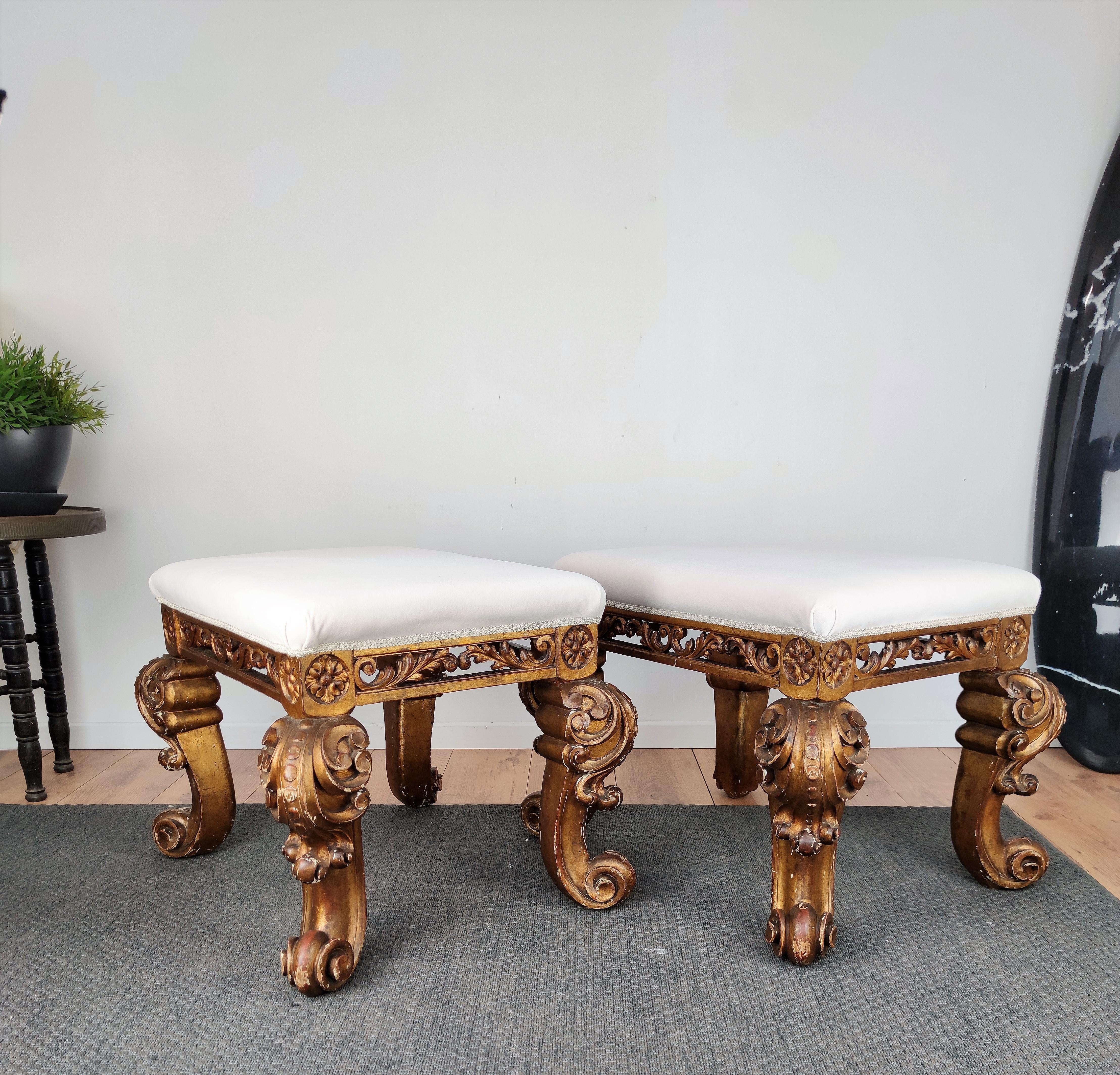 Beautiful, very ornately hand carved wooden, pair of antique 17th century Italian Baroque stools with a gilt finish and newly upholstered white fabric to magnify the workmanship, history, detail and color of the incredible decors of the carved