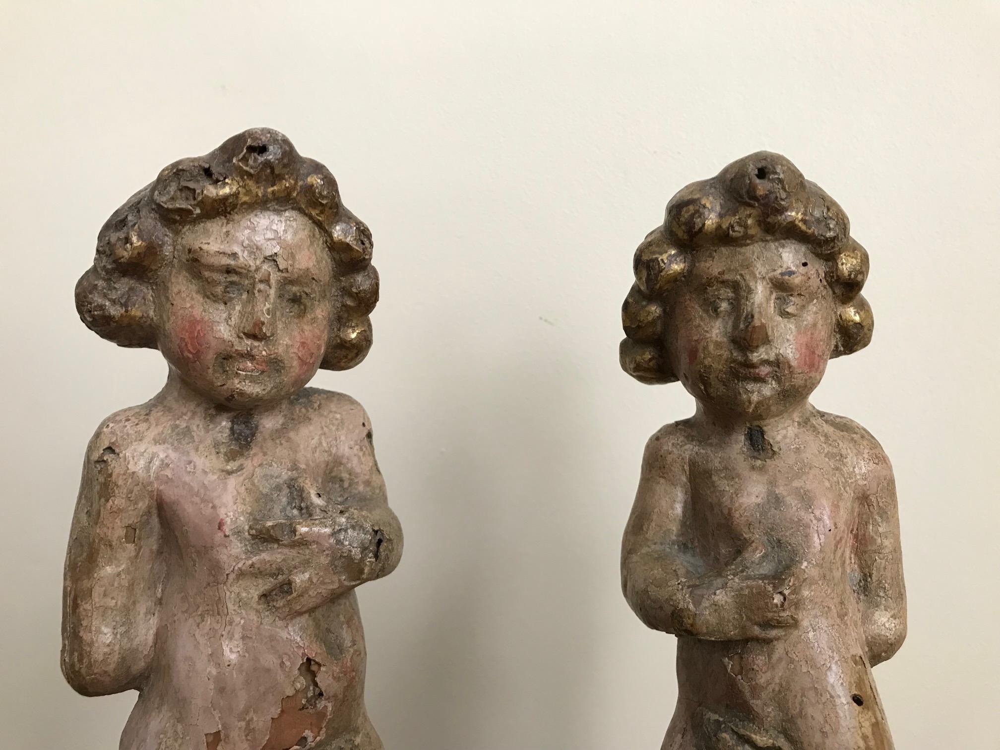Wonderful pair of Italian Baroque carved putti with original polychrome (painted surface) and gilding. These two have quite a bit of personality, each with his individual expression. The stance is unusual with one arm behind the back and the other