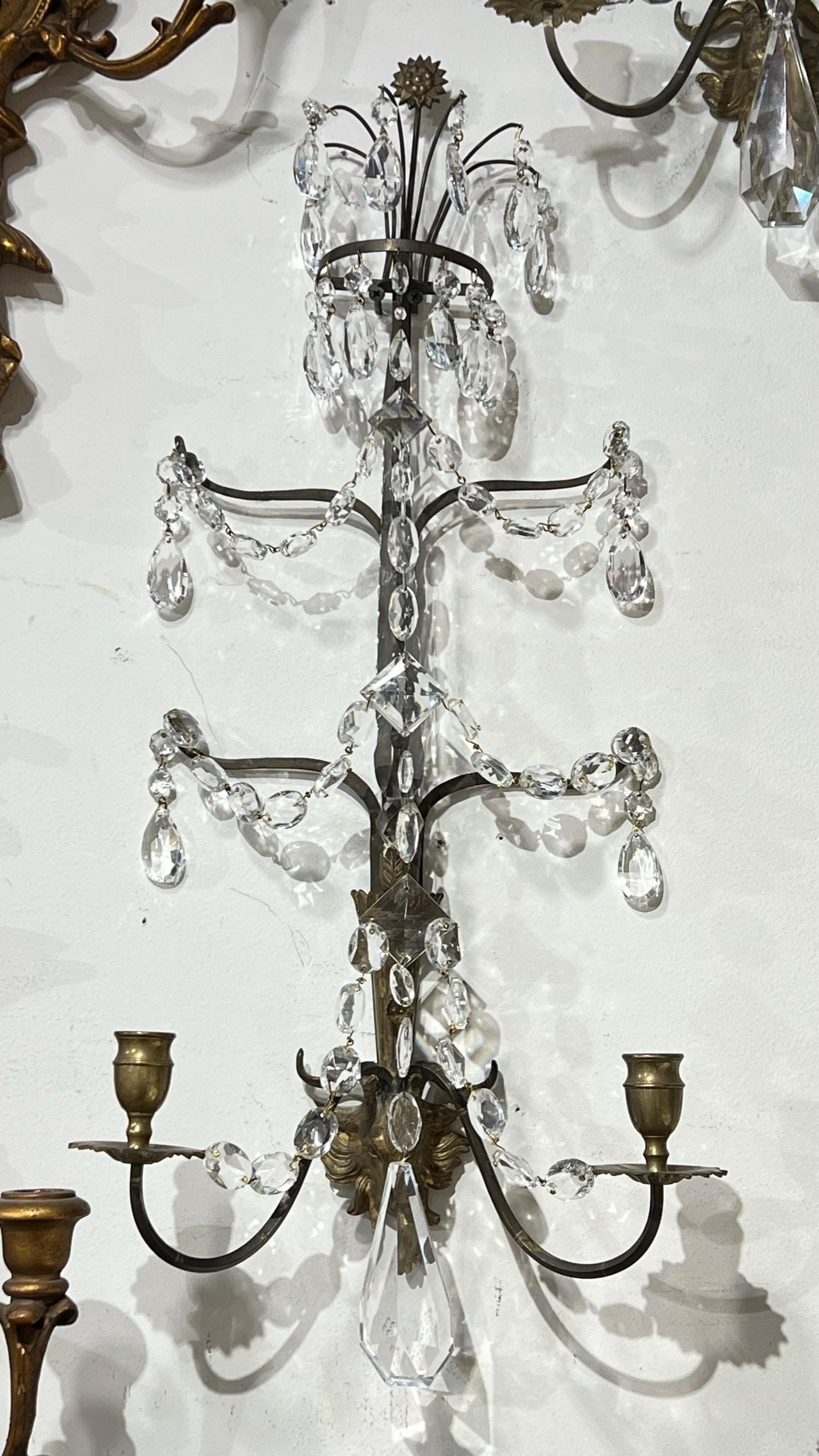Pair 19th century French bronze wall lights in the Louis XVI style with torch form with ram head at base and surmounted by starburst, with extensive faceted crystals including swags, pear shaped drops and tall spire along the spine. May be