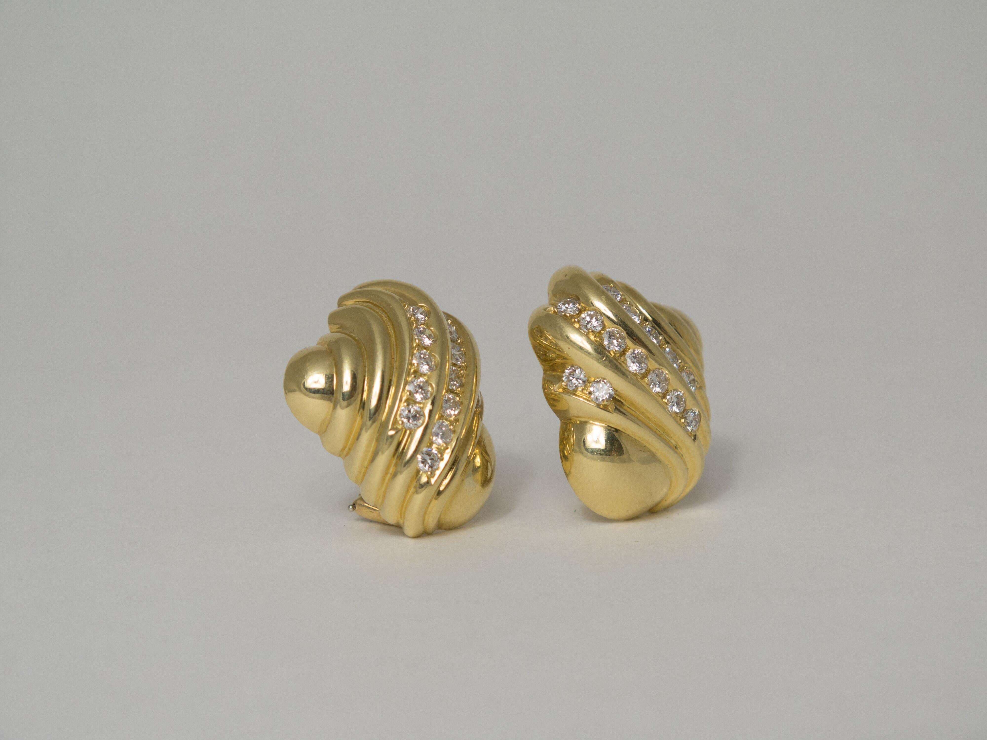 A classic pair of turbo shell shaped clip-on earrings in heavy 18k yellow gold accented with a curved band of diamonds that follow the natural lines of the shell form. 
The earrings are heavy, weighing a total of 31.46 grams. However, they are easy
